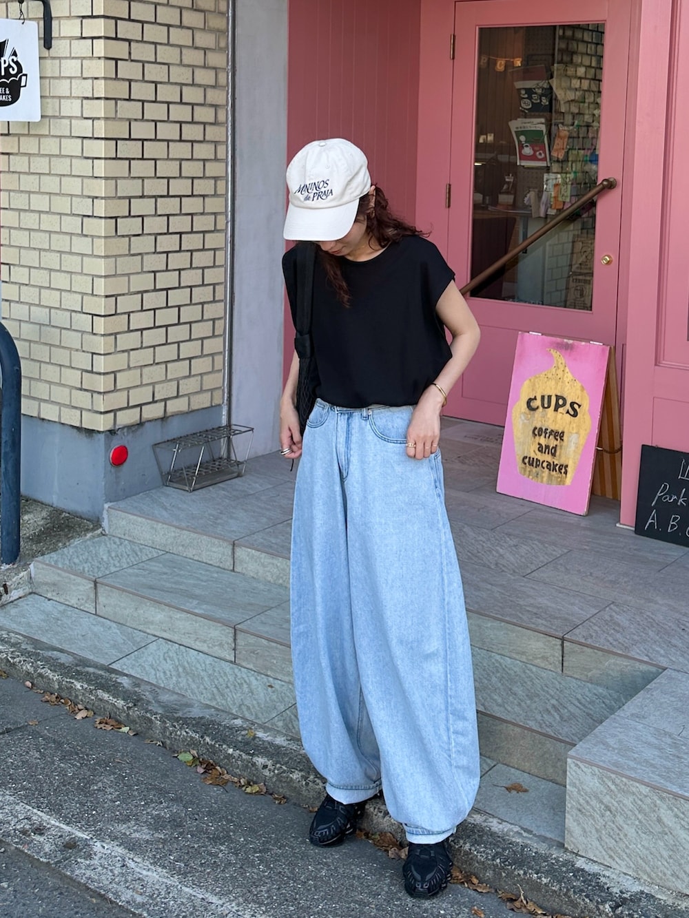 ブラック系のTシャツ/カットソー、ブルー系のデニムパンツ、ブラック系のショルダーバッグを着用したレディースの夏コーディネートの2枚目の写真