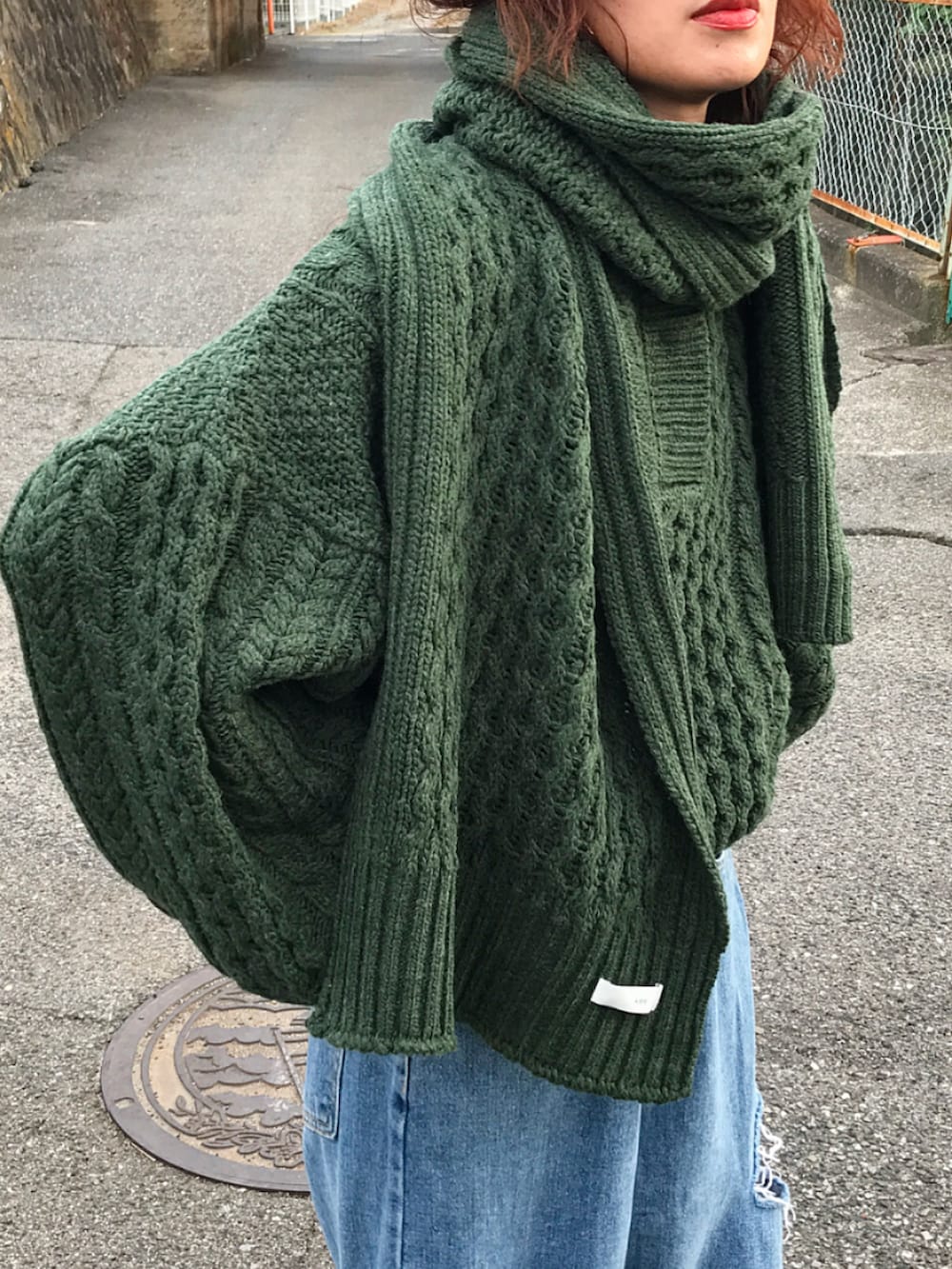 グリーン系のニット/セーター、ブルー系のデニムパンツ、ブラック系のショルダーバッグを着用したレディースの秋コーディネートの3枚目の写真