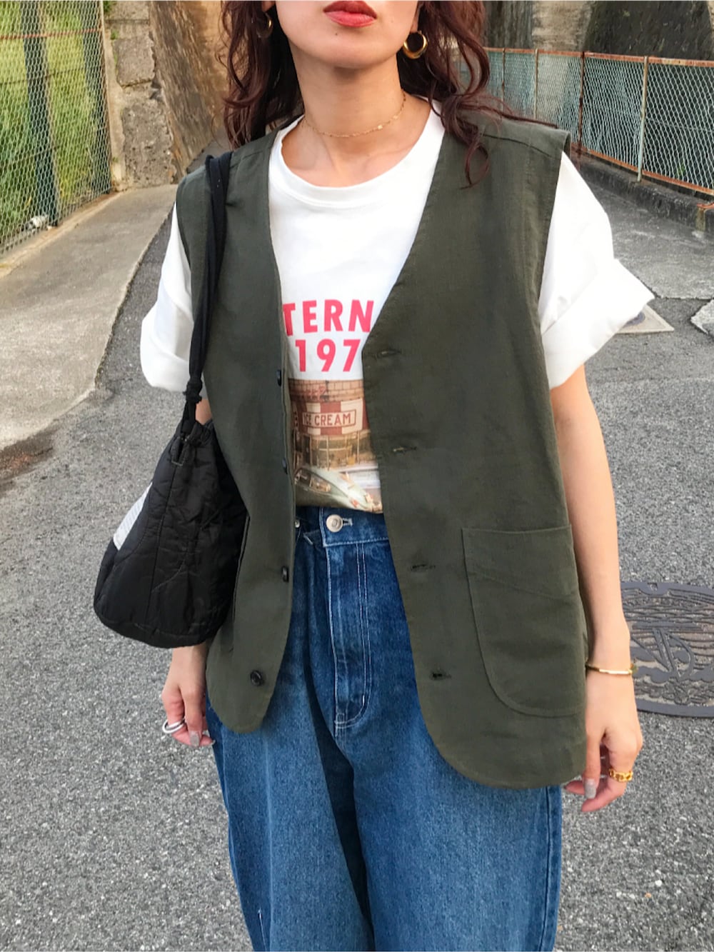 グリーン系のベスト、ホワイト系のTシャツ/カットソー、ブルー系のデニムパンツを着用したレディースの春コーディネートの2枚目の写真