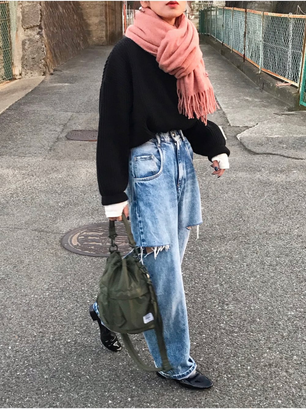 ブラック系のニット/セーター、ブルー系のデニムパンツ、ホワイト系のTシャツ/カットソーを着用したレディースの秋コーディネートの2枚目の写真