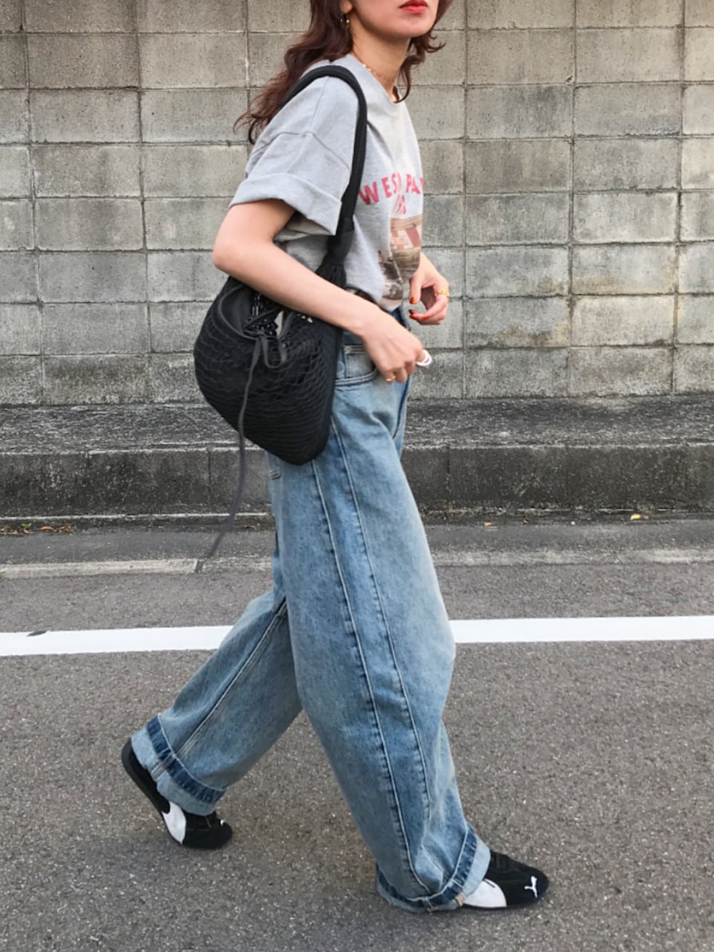 グレー系のTシャツ/カットソー、ブルー系のデニムパンツ、ブラック系のショルダーバッグを着用したレディースの春コーディネートの2枚目の写真