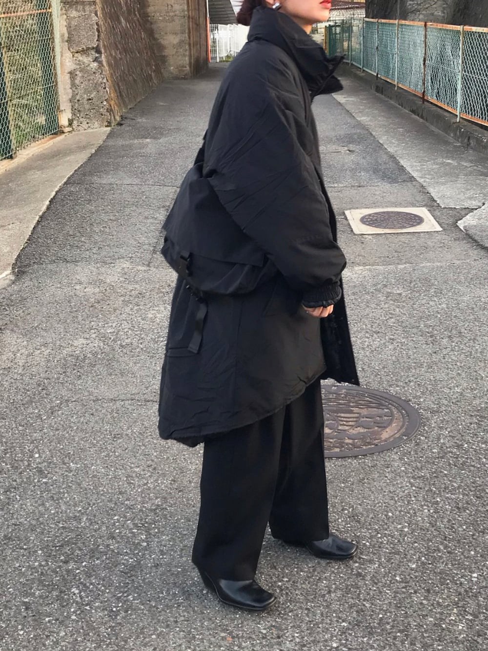 ブラック系のダウンジャケット/コート、ブラック系のショルダーバッグ、ホワイト系のTシャツ/カットソーを着用したレディースの冬コーディネートの2枚目の写真