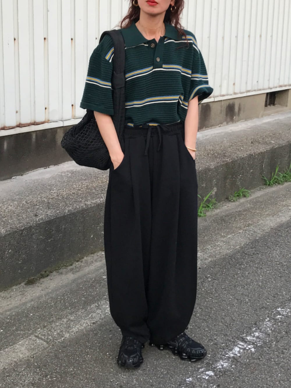 グリーン系のポロシャツ、ブラック系のスウェットパンツ、ブラック系のショルダーバッグを着用したレディースの夏コーディネートの2枚目の写真