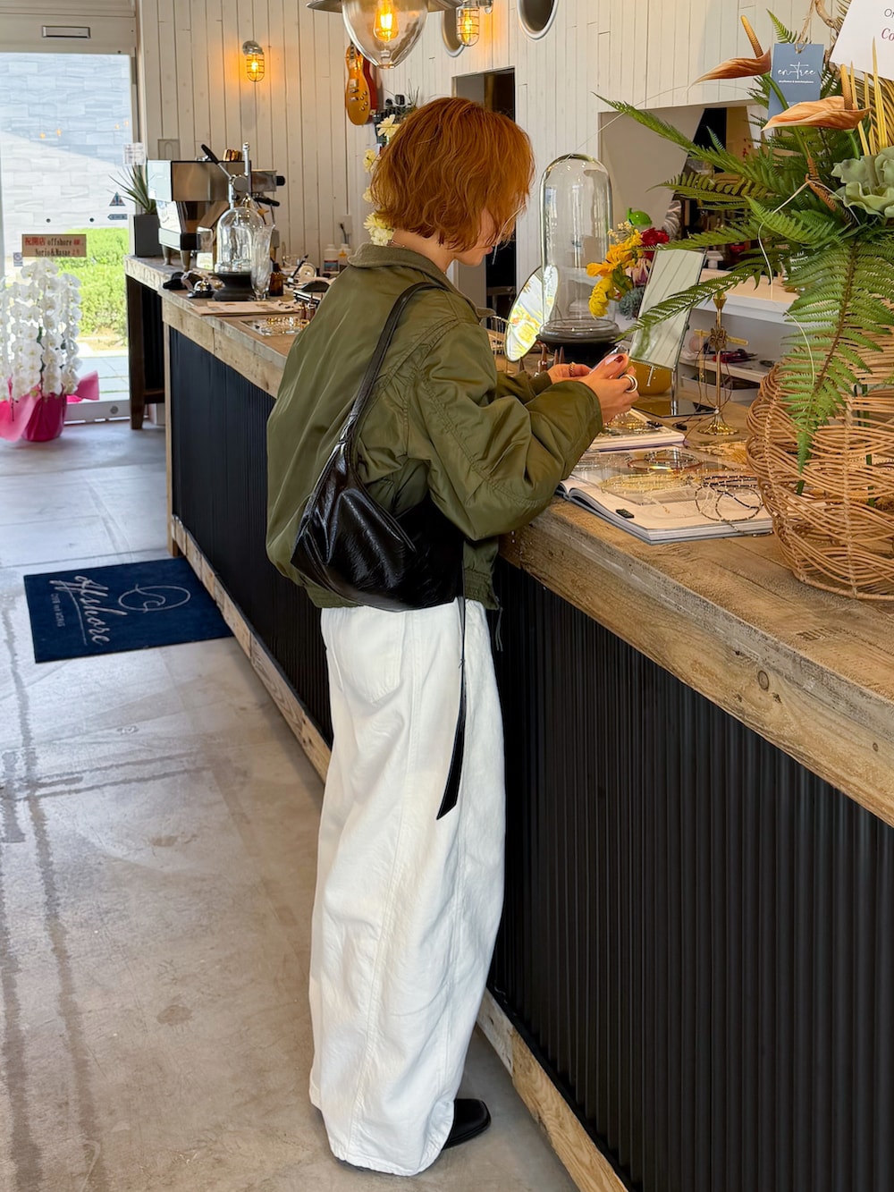 ブラック系のブーツ、グリーン系のMA-1、ホワイト系のデニムパンツを着用したレディースの春コーディネートの2枚目の写真