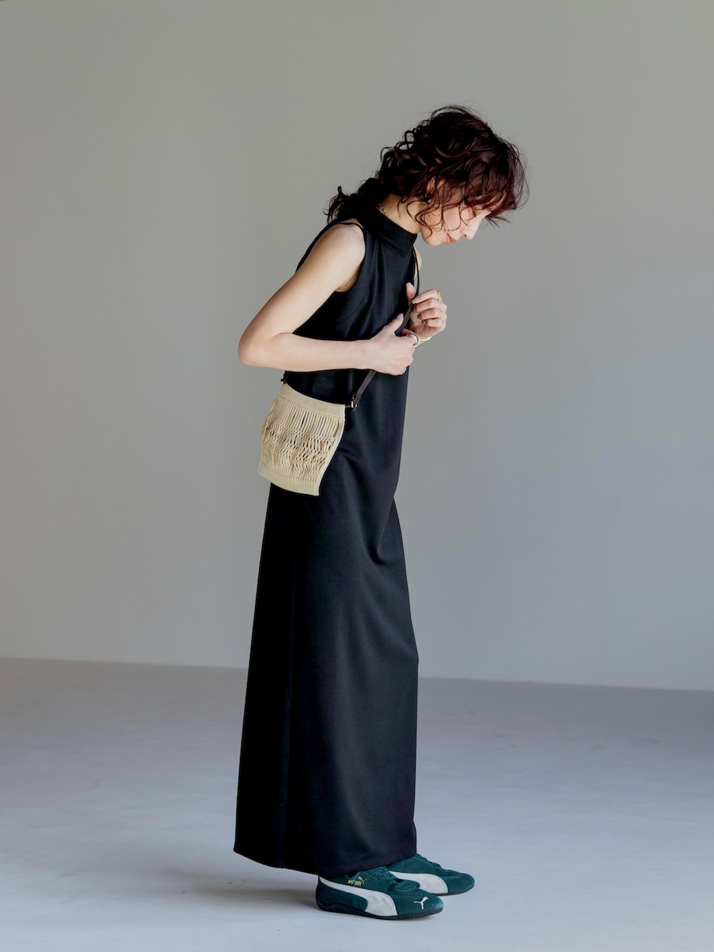 ブラック系のワンピース、ベージュ系のバッグ、グリーン系のスニーカーを着用したレディースの春コーディネートの2枚目の写真