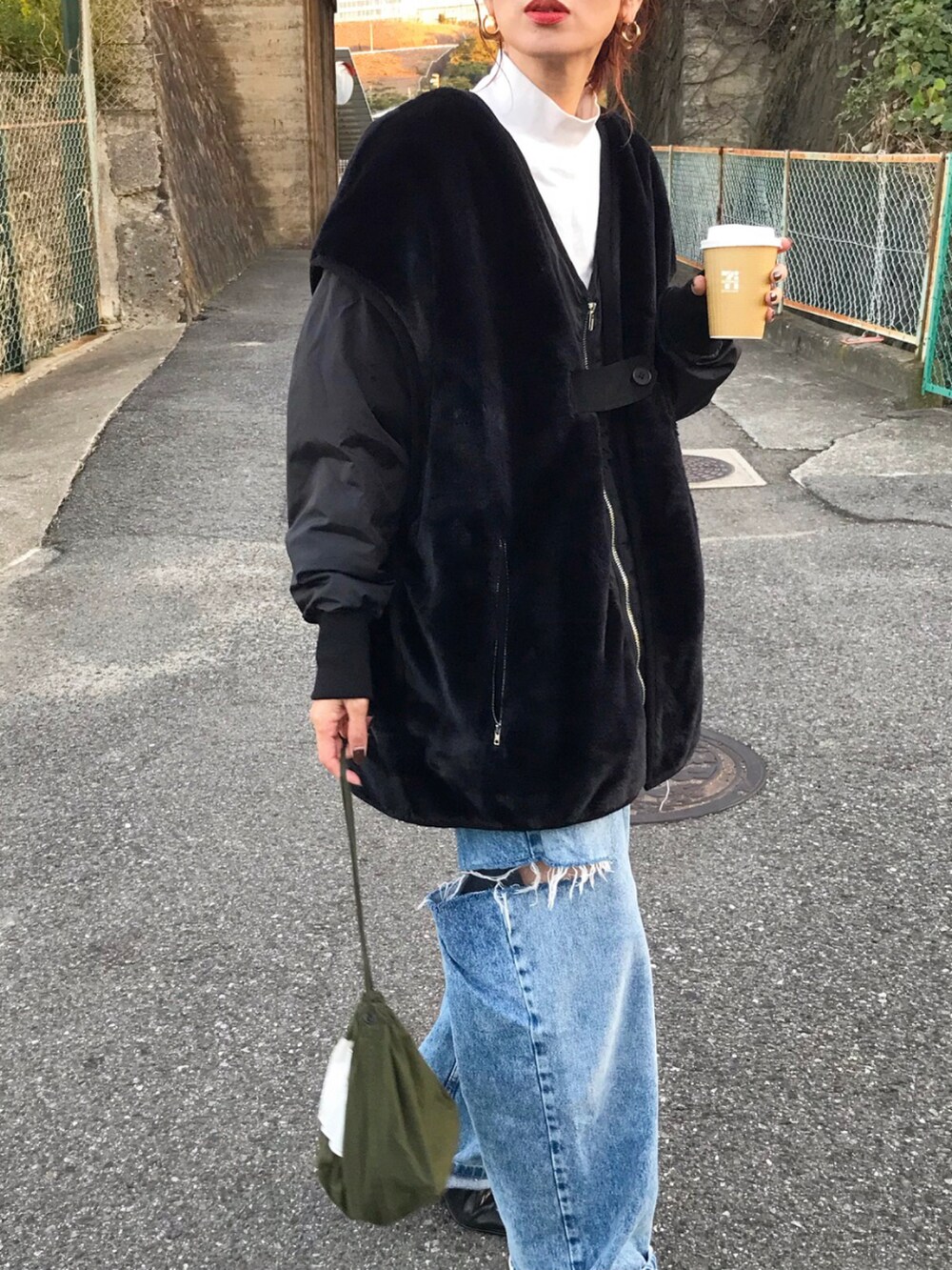 ブラック系のブルゾン、ホワイト系のTシャツ/カットソー、ブルー系のデニムパンツを着用したレディースの秋コーディネートの2枚目の写真