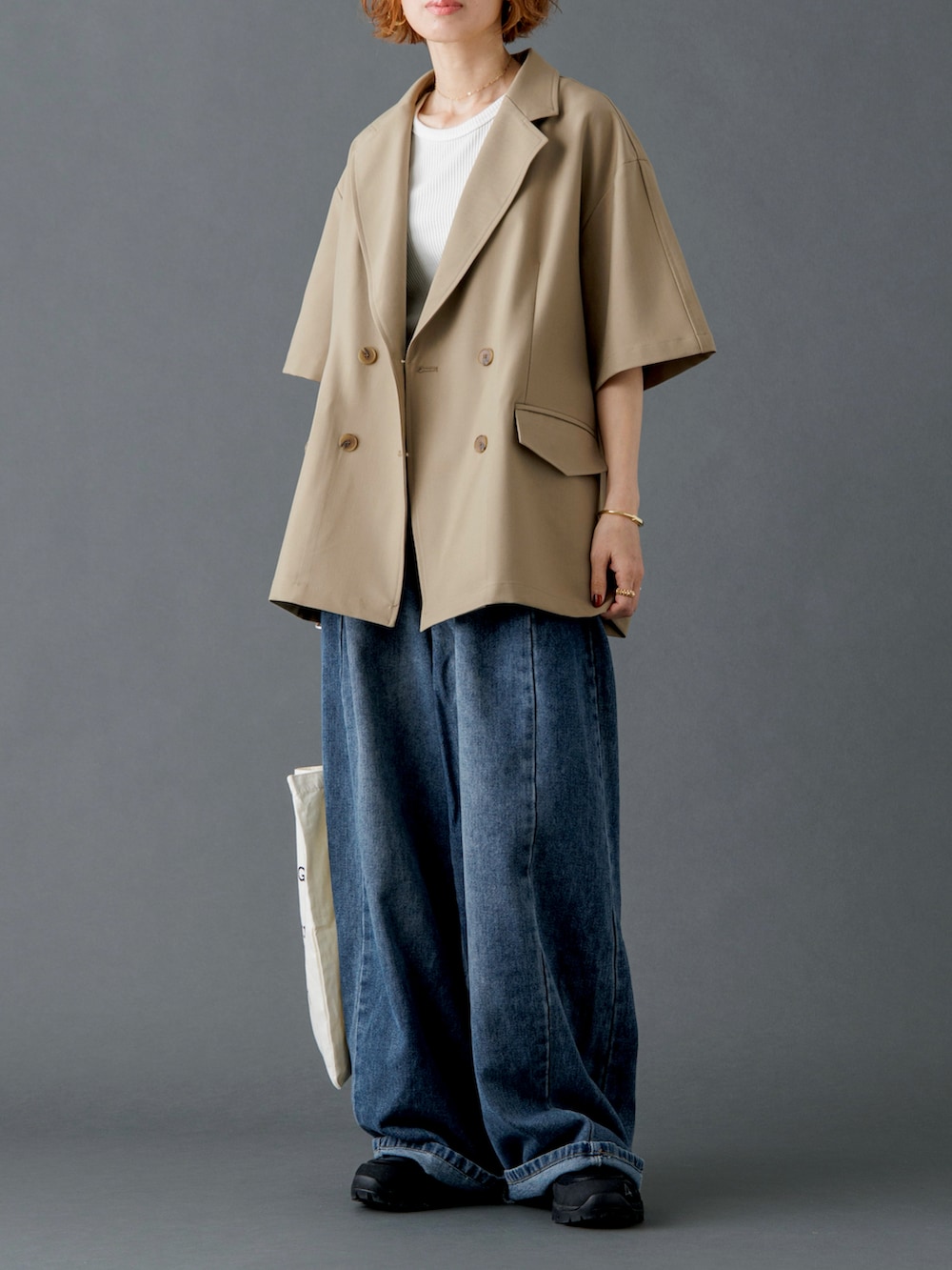 ベージュ系のテーラードジャケット、ブルー系のデニムパンツ、ホワイト系のトートバッグを着用したレディースの春コーディネートの2枚目の写真