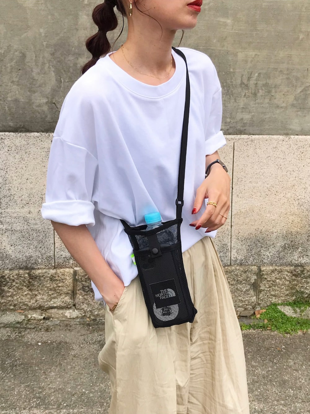 ホワイト系のTシャツ/カットソー、ベージュ系のパンツ、ブラック系のショルダーバッグを着用したレディースの夏コーディネートの2枚目の写真