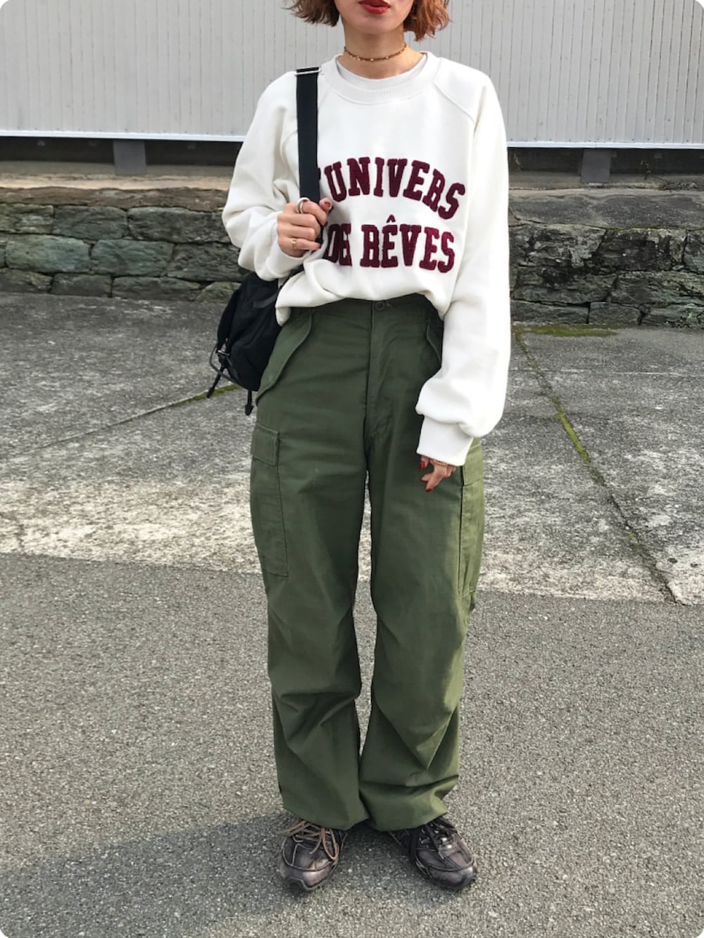 ブラック系のバックパック/リュック、ホワイト系のスウェット、グリーン系のカーゴパンツを着用したレディースの冬コーディネートの2枚目の写真