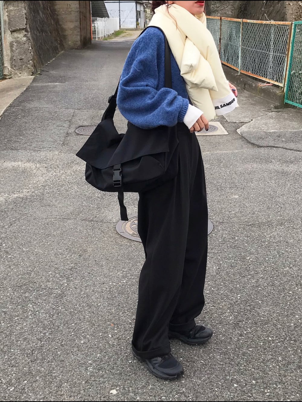 ブルー系のニット/セーター、ブラック系のパンツ、ブラック系のショルダーバッグを着用したレディースの秋コーディネートの2枚目の写真