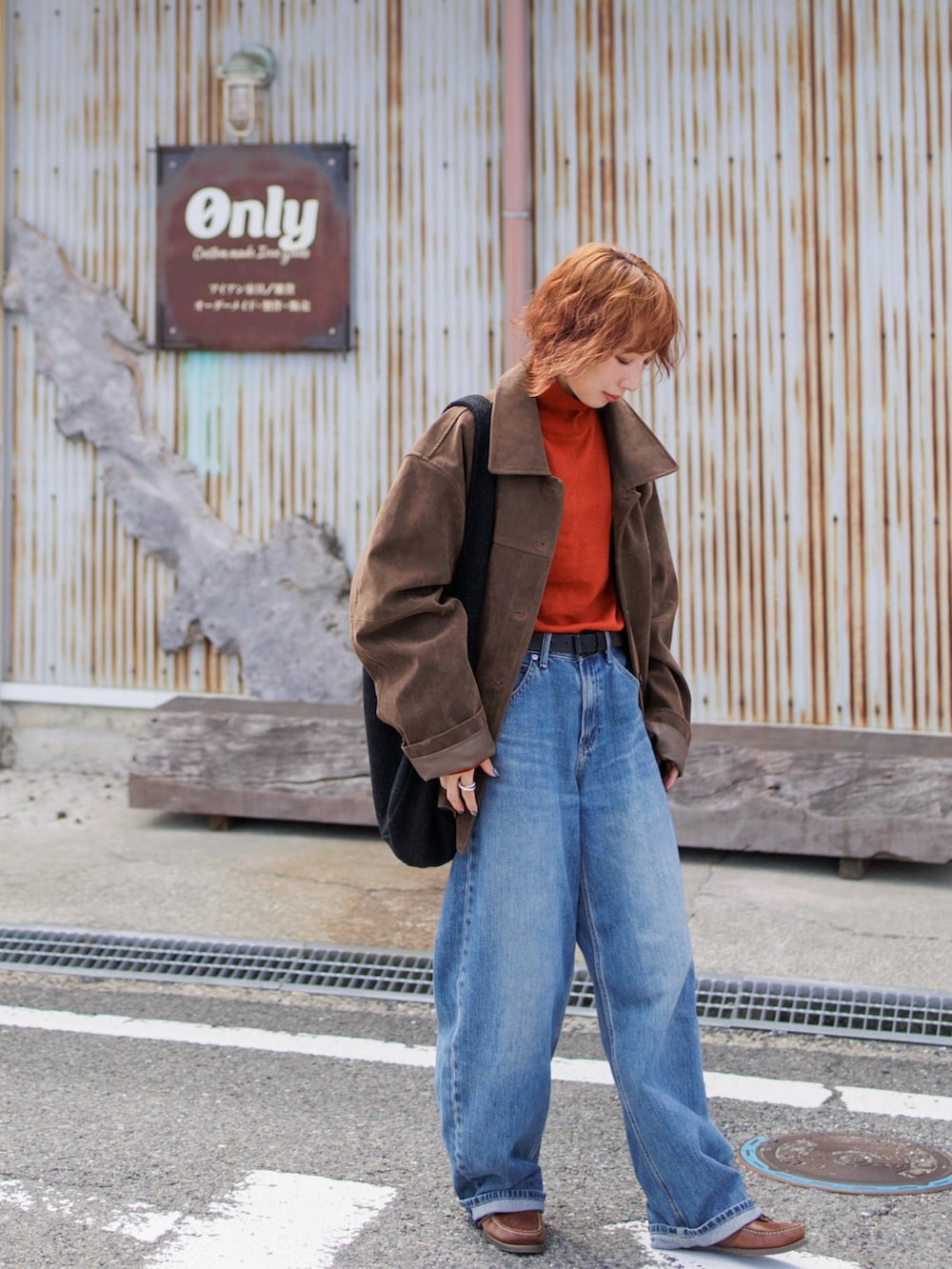 ブラウン系のモカシン/デッキシューズ、オレンジ系のニット/セーター、ブラウン系のジャケット/アウターを着用したレディースの秋コーディネートの2枚目の写真