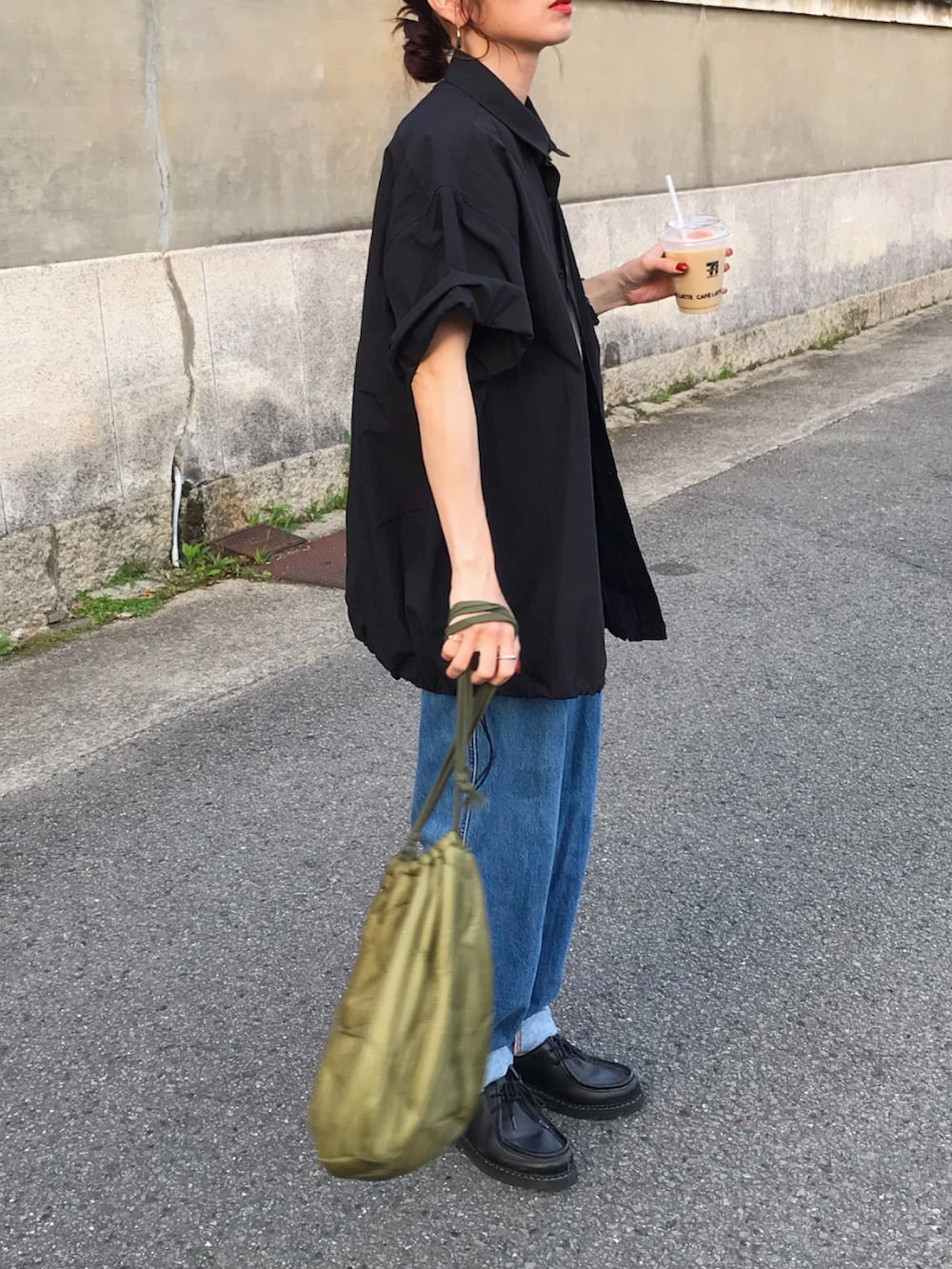 ブラック系のシャツ/ブラウス、グリーン系のショルダーバッグ、ブルー系のデニムパンツを着用したレディースの春コーディネートの2枚目の写真