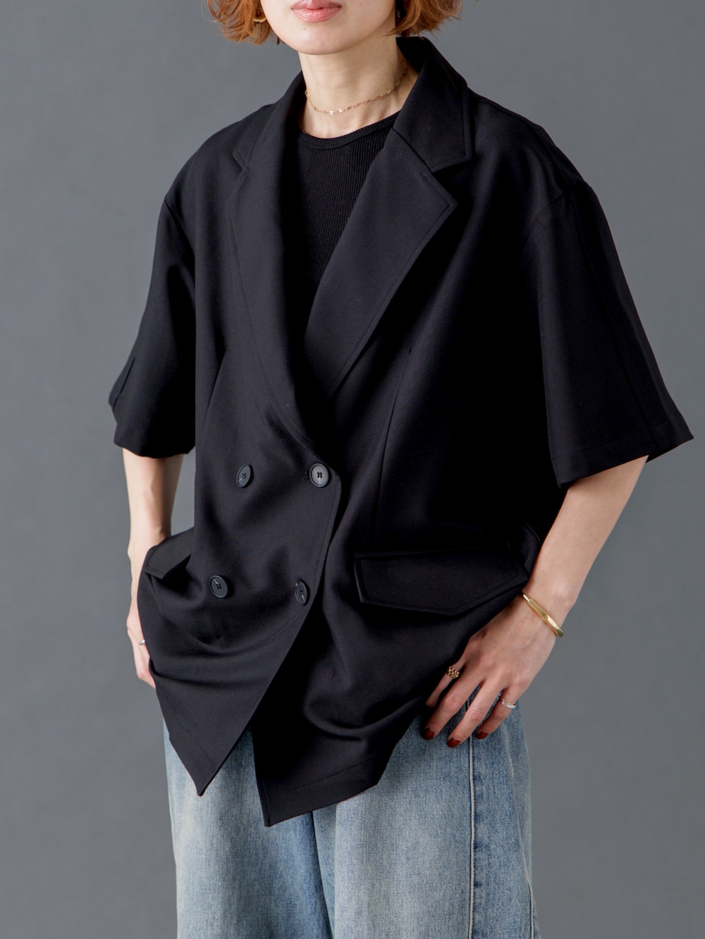 ブラック系のテーラードジャケット、ブルー系のデニムパンツ、ブラウン系のスニーカーを着用したレディースの春コーディネートの3枚目の写真