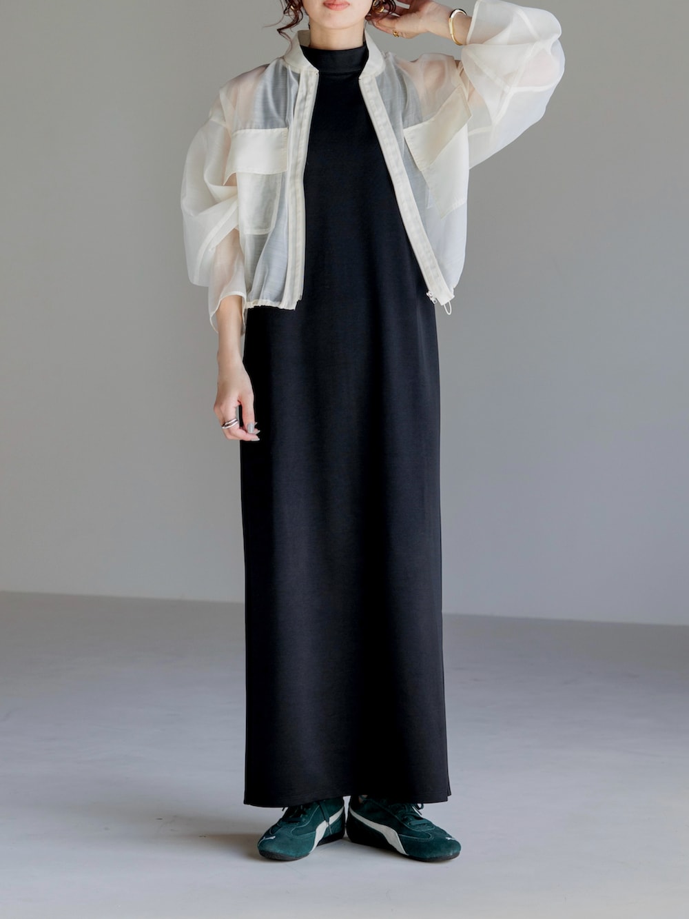 ブラック系のワンピース、ホワイト系のブルゾン、グリーン系のスニーカーを着用したレディースの春コーディネートの2枚目の写真