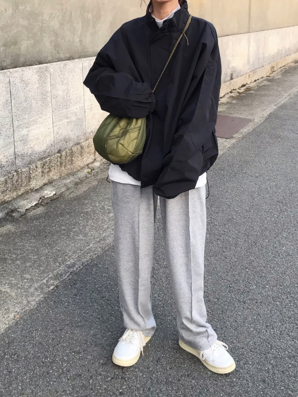 ブラック系のジャケット/アウター、グレー系のスウェットパンツ、ホワイト系のスニーカーを着用したレディースの冬コーディネートの2枚目の写真