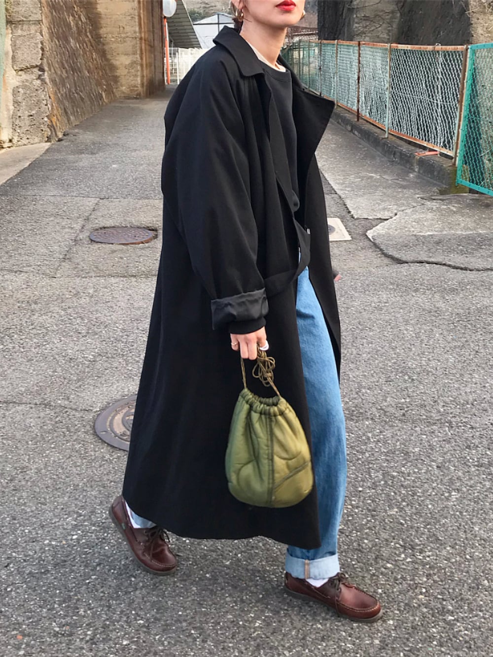 ブラック系のスウェット、ブラック系のトレンチコート、ブルー系のデニムパンツを着用したレディースの冬コーディネートの2枚目の写真