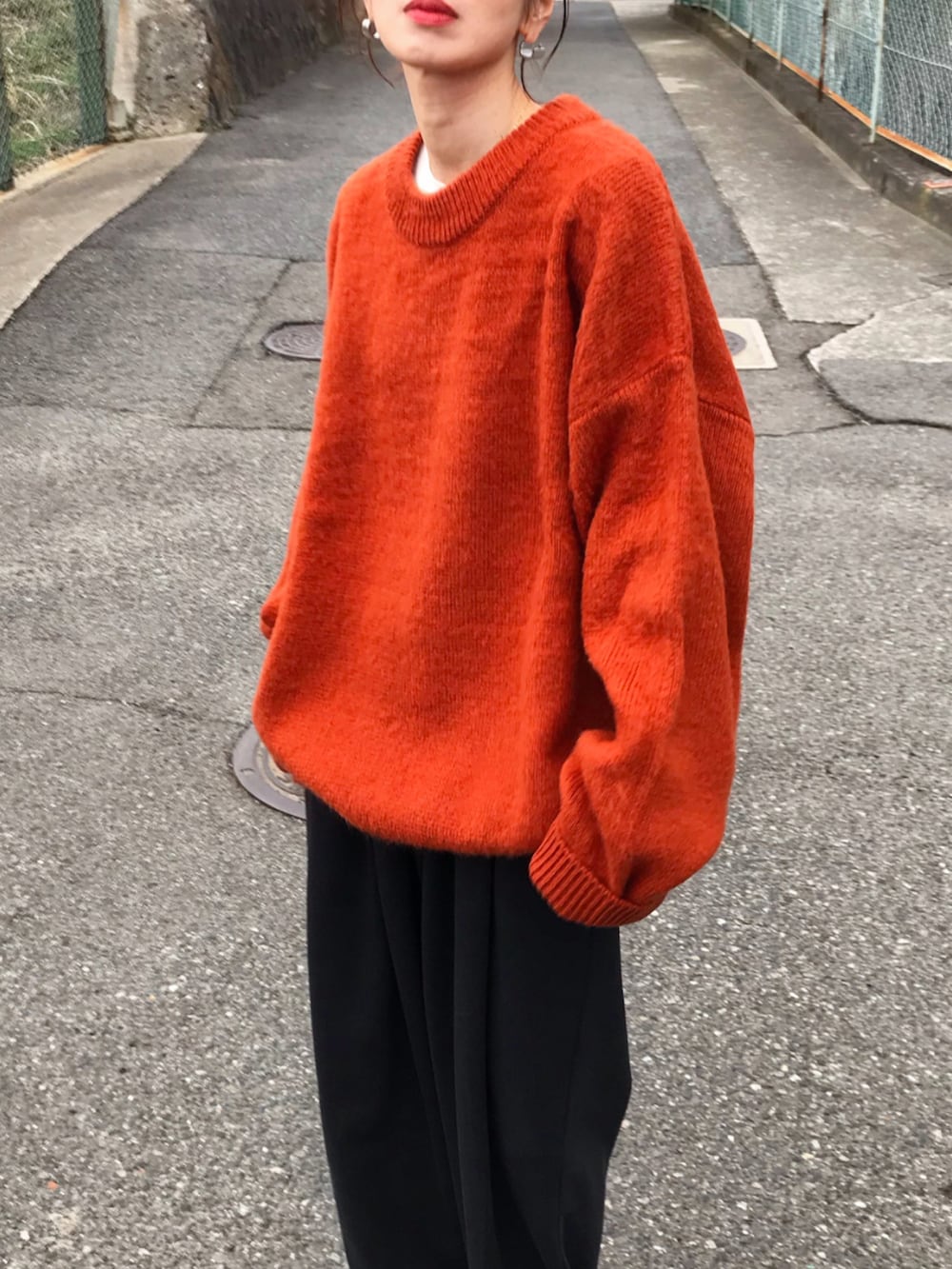 ブラック系のジャケット/アウター、オレンジ系のニット/セーター、ブラック系のショルダーバッグを着用したレディースの冬コーディネートの3枚目の写真