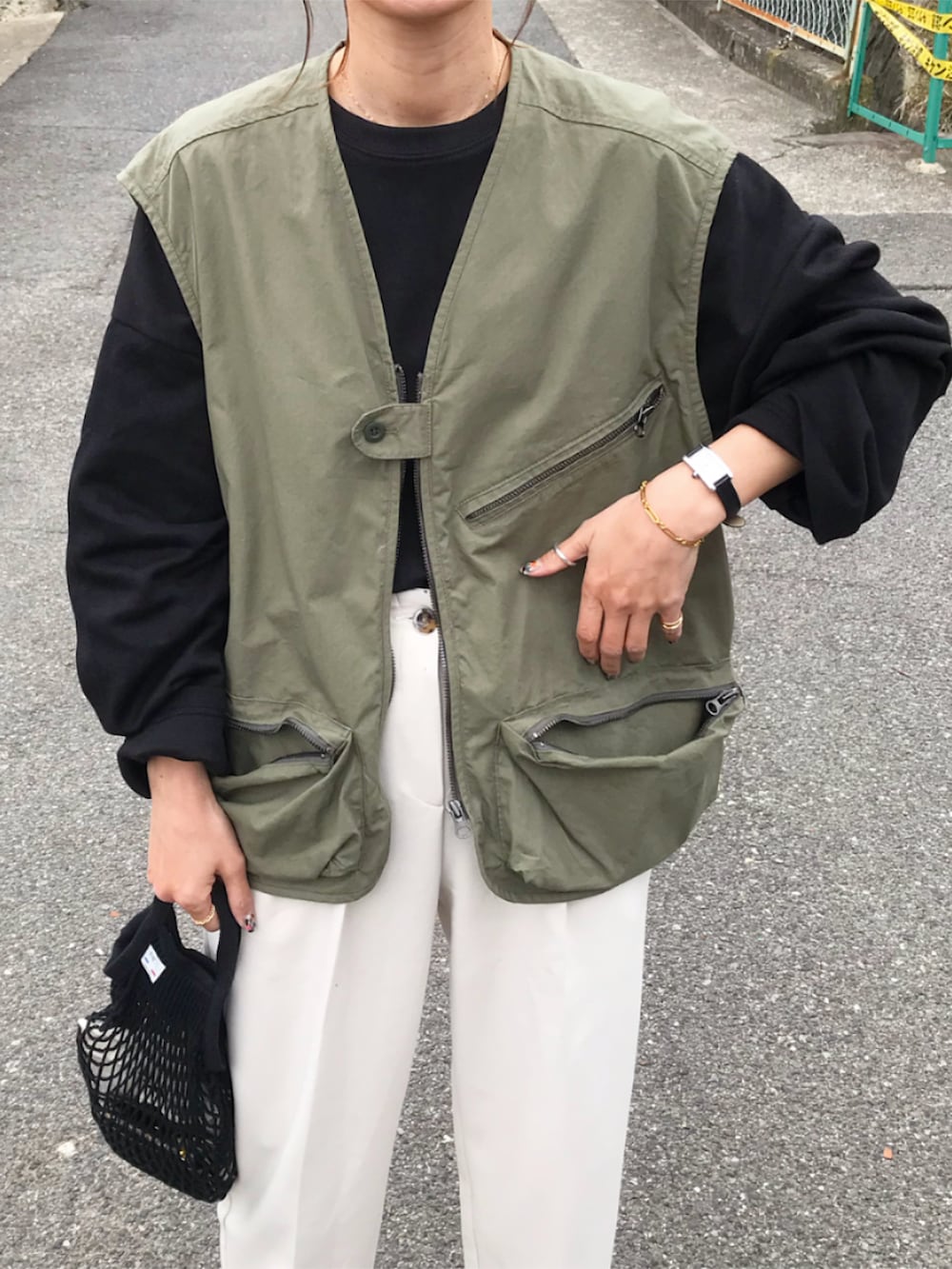 グリーン系のベスト、ブラック系のTシャツ/カットソー、ホワイト系のパンツを着用したレディースの春コーディネートの3枚目の写真