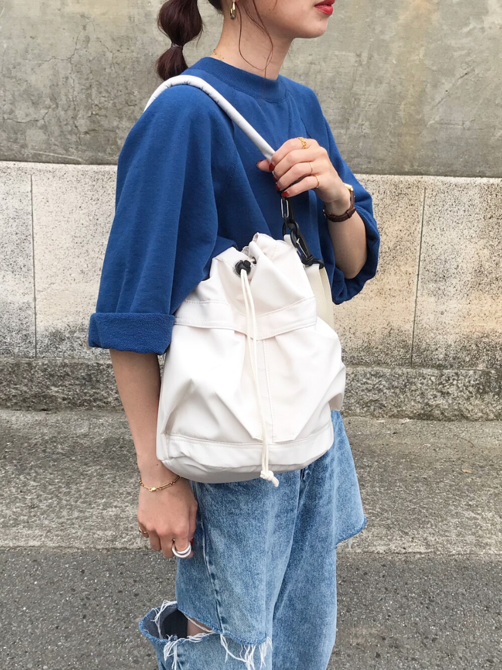 ブルー系のTシャツ/カットソー、ブルー系のデニムパンツ、ホワイト系のショルダーバッグを着用したレディースの春コーディネートの2枚目の写真