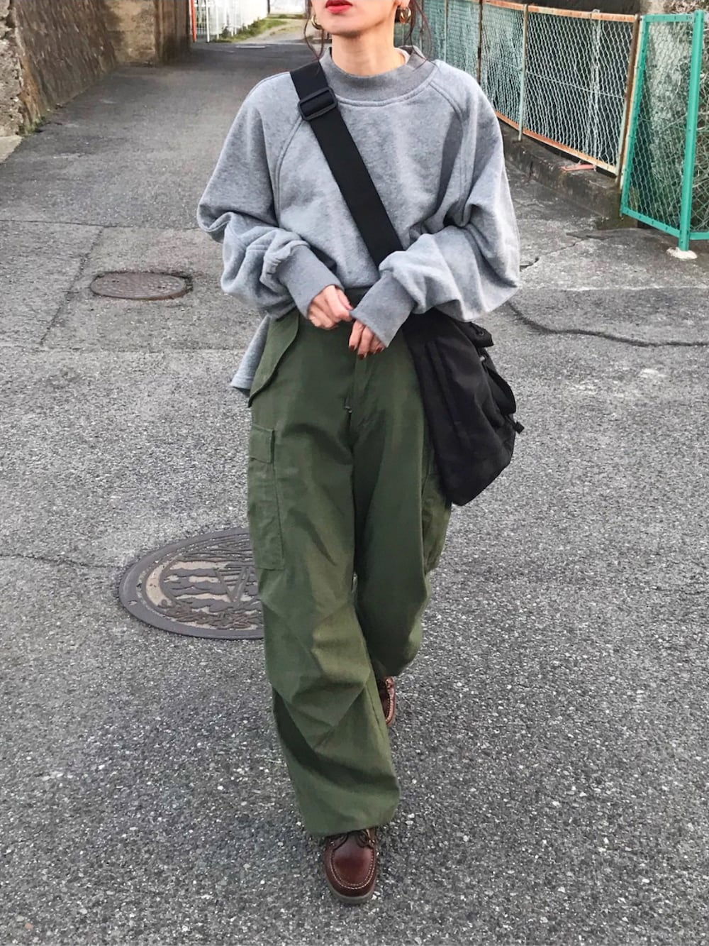 グレー系のスウェット、グリーン系のカーゴパンツ、ブラック系のショルダーバッグを着用したレディースの冬コーディネートの2枚目の写真