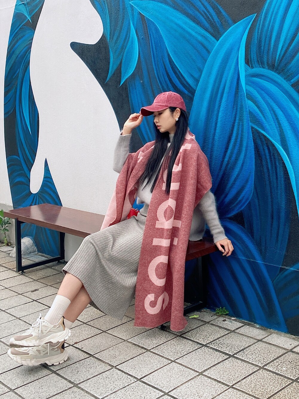 グレー系のスカート、ベージュ系のスニーカー、ピンク系のストール/ショールを着用したレディースの冬コーディネートの2枚目の写真