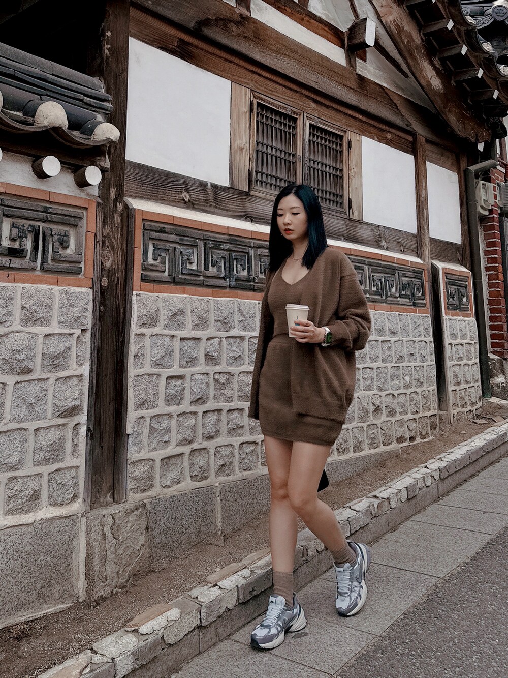 シルバー系のスニーカー、ブラウン系のキャミソール、ブラック系のショルダーバッグを着用したレディースの春コーディネートの3枚目の写真