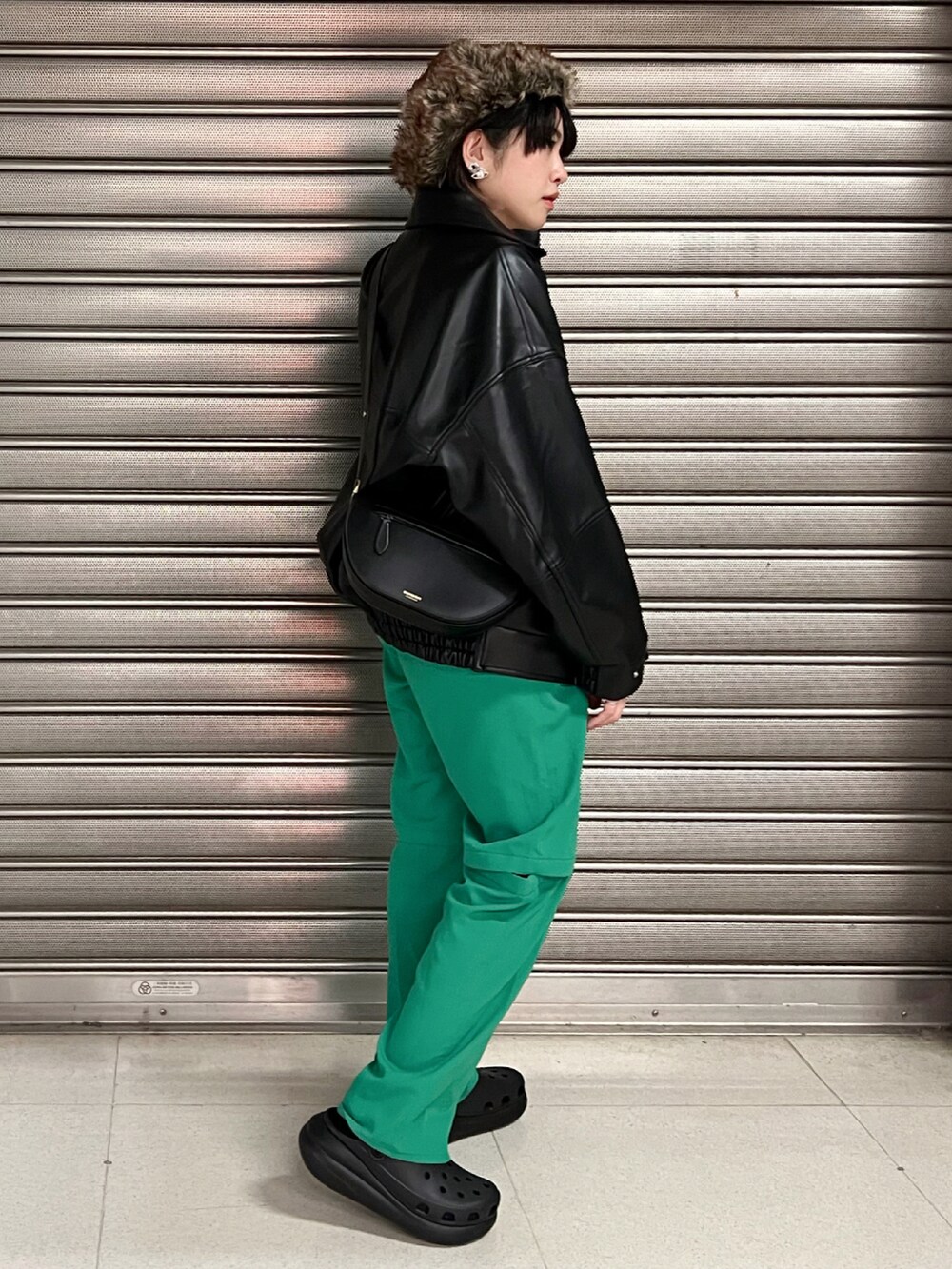 グリーン系のパンツ、ブラック系のサンダル、ブラック系のブルゾンを着用したレディースの冬コーディネートの3枚目の写真