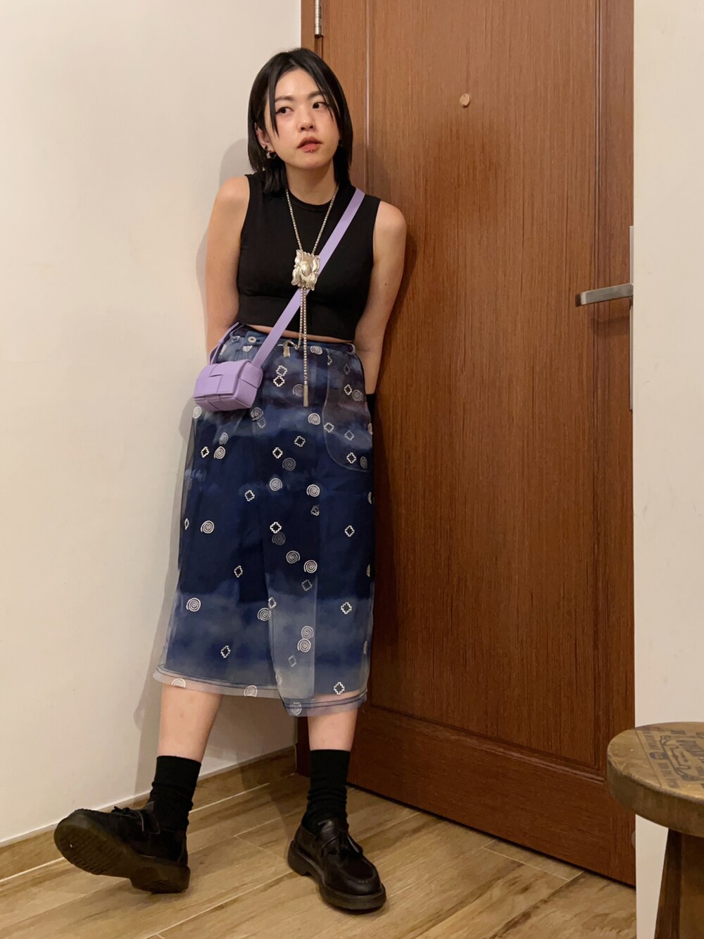 ブルー系のスカート、ブラック系のタンクトップ、ブラック系のローファーを着用したレディースの夏コーディネートの3枚目の写真