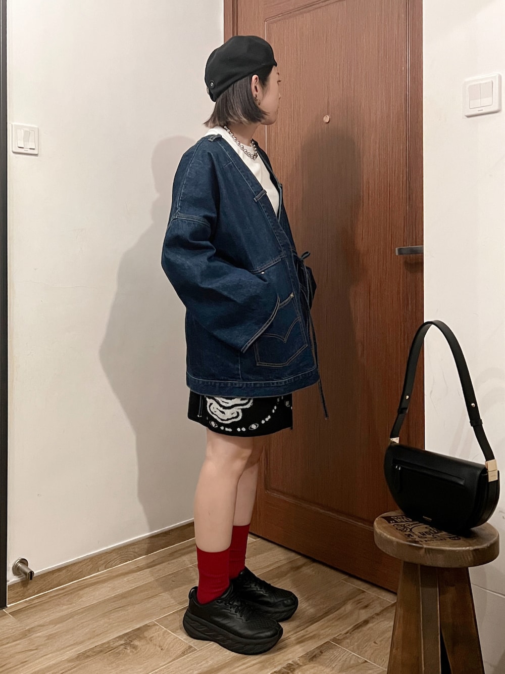 ブルー系のデニムジャケット、ブラック系のハンドバッグ、ブラック系のスニーカーを着用したレディースの秋コーディネートの3枚目の写真