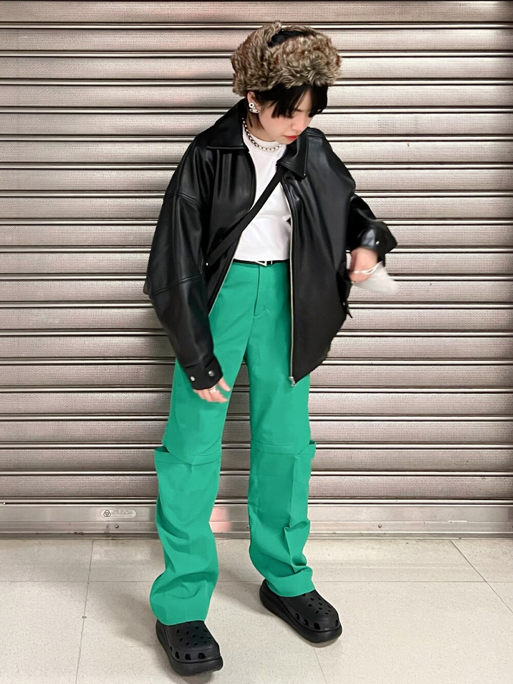 グリーン系のパンツ、ブラック系のサンダル、ブラック系のブルゾンを着用したレディースの冬コーディネートの2枚目の写真