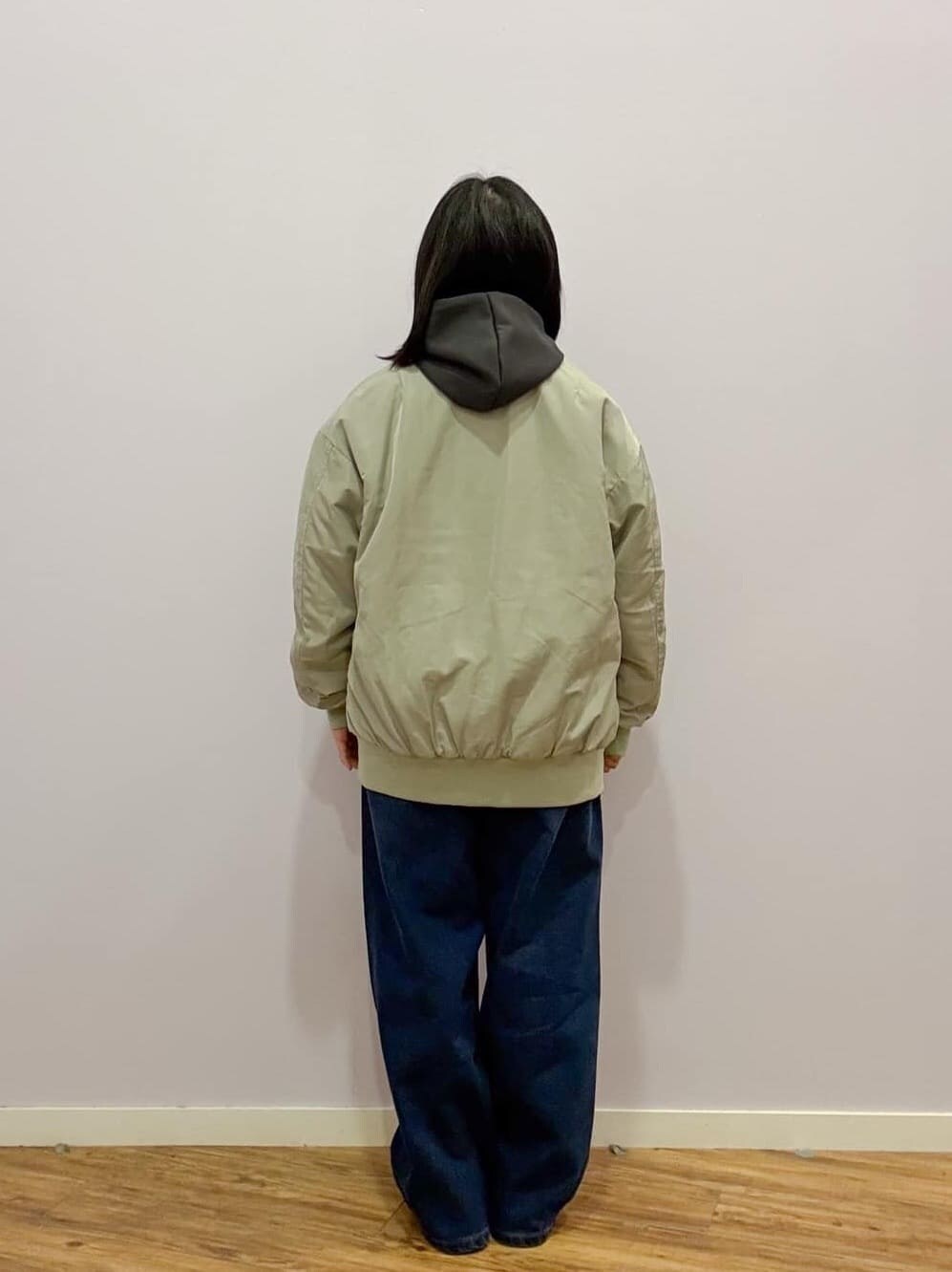 グリーン系のブルゾン、グレー系のパーカー、ブルー系のデニムパンツを着用したレディースの冬コーディネートの3枚目の写真
