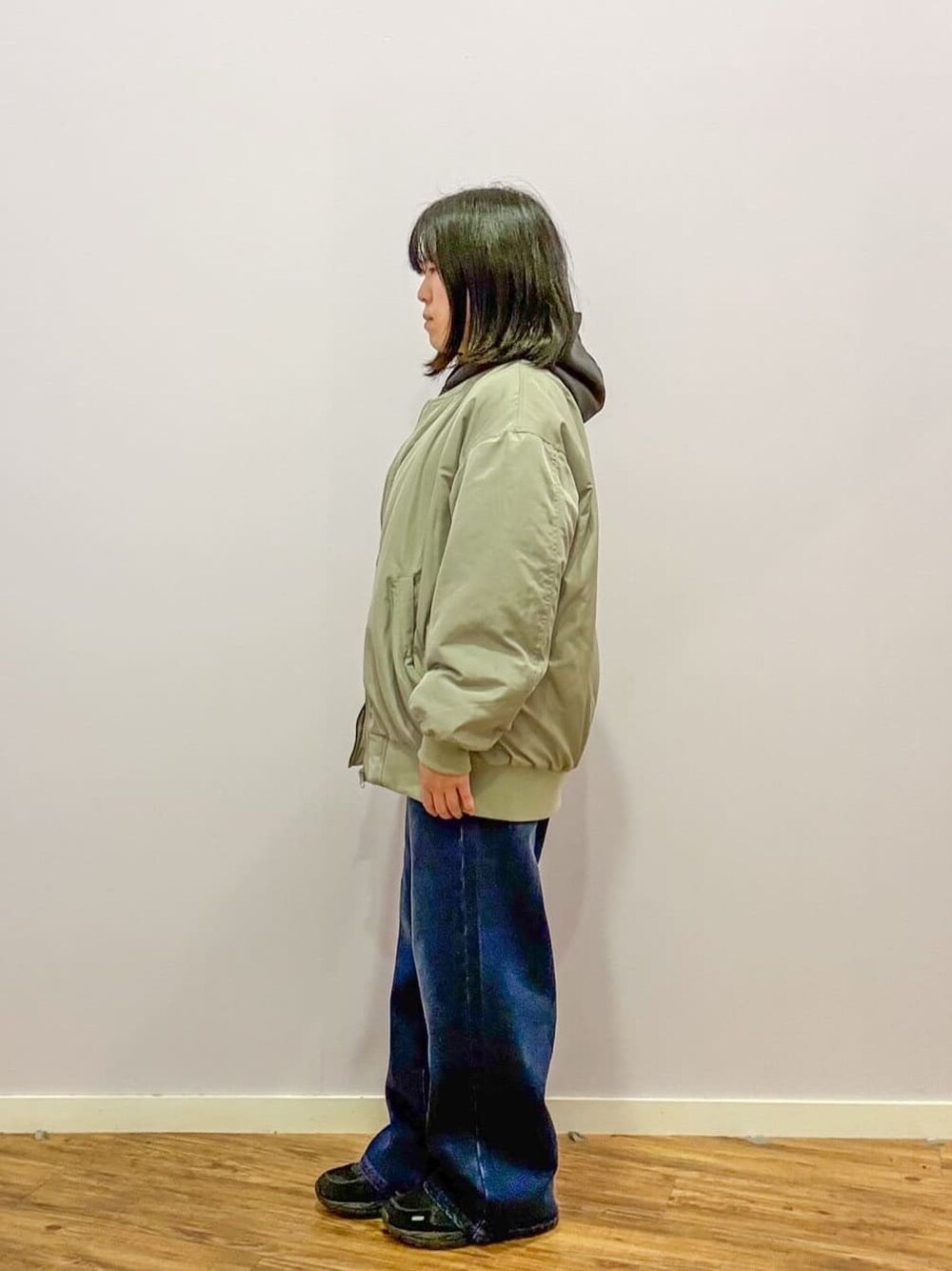 グリーン系のブルゾン、グレー系のパーカー、ブルー系のデニムパンツを着用したレディースの冬コーディネートの2枚目の写真