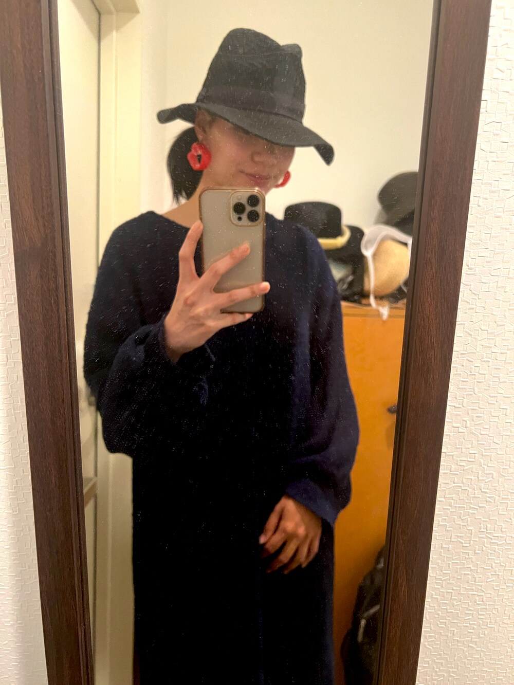 レッド系のイヤリング、ブラック系のハットを着用したレディースの秋コーディネートの2枚目の写真