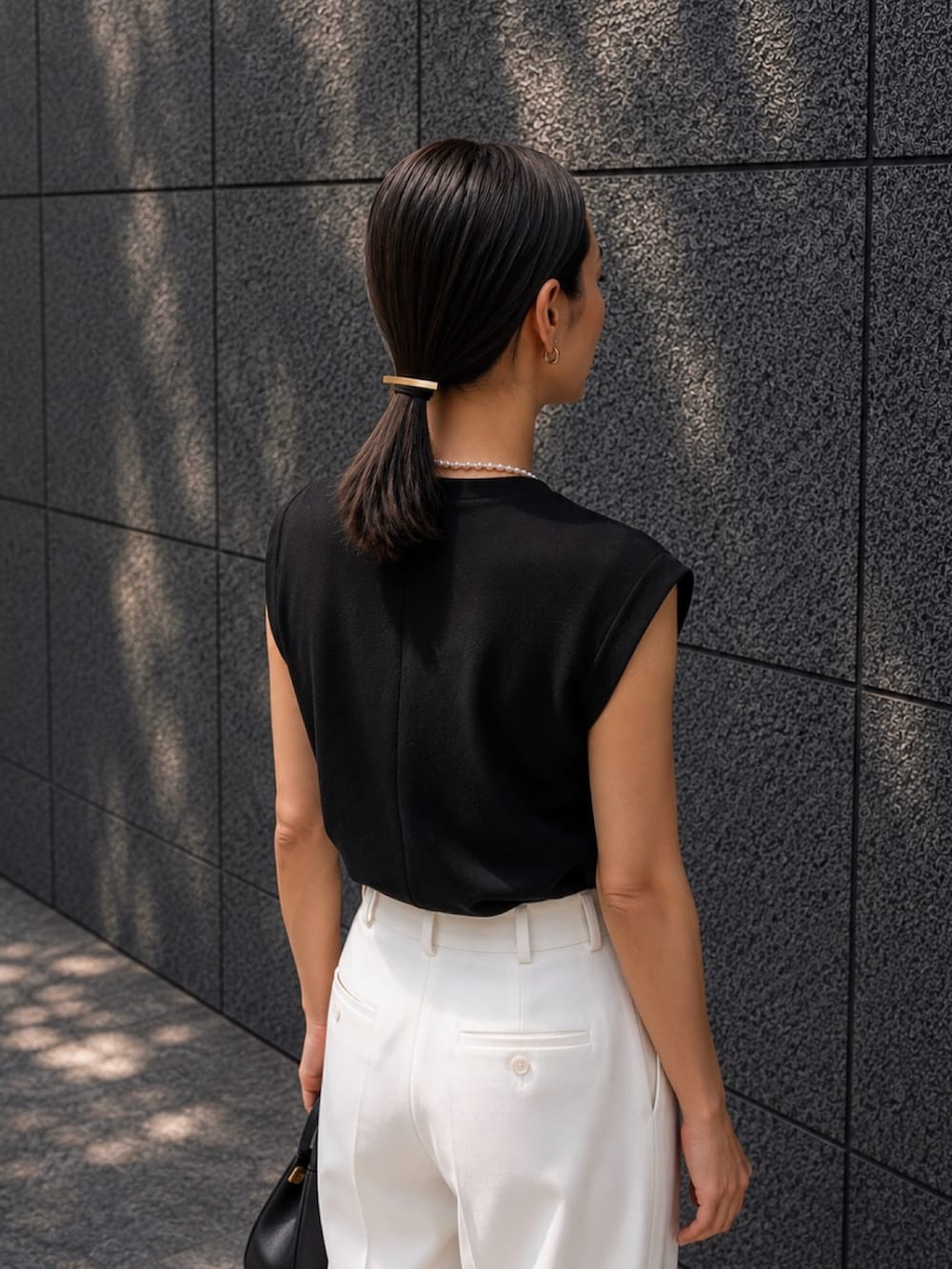 ホワイト系のパンツ、ブラック系のサンダル、ゴールド系のヘアゴムを着用したレディースの夏コーディネートの3枚目の写真