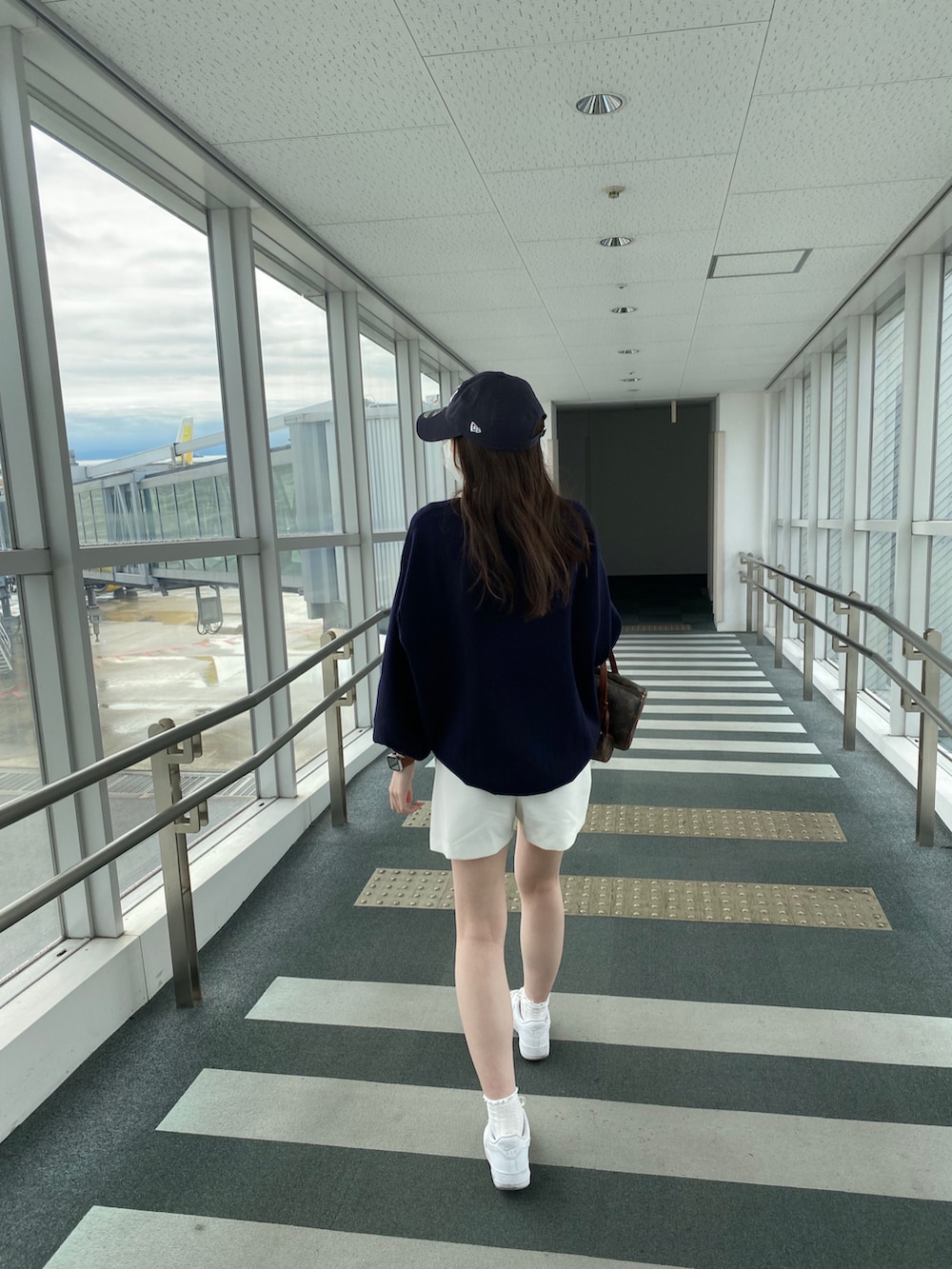 ブルー系のニット/セーター、ホワイト系のパンツ、ホワイト系のスニーカーを着用したレディースの春コーディネートの2枚目の写真