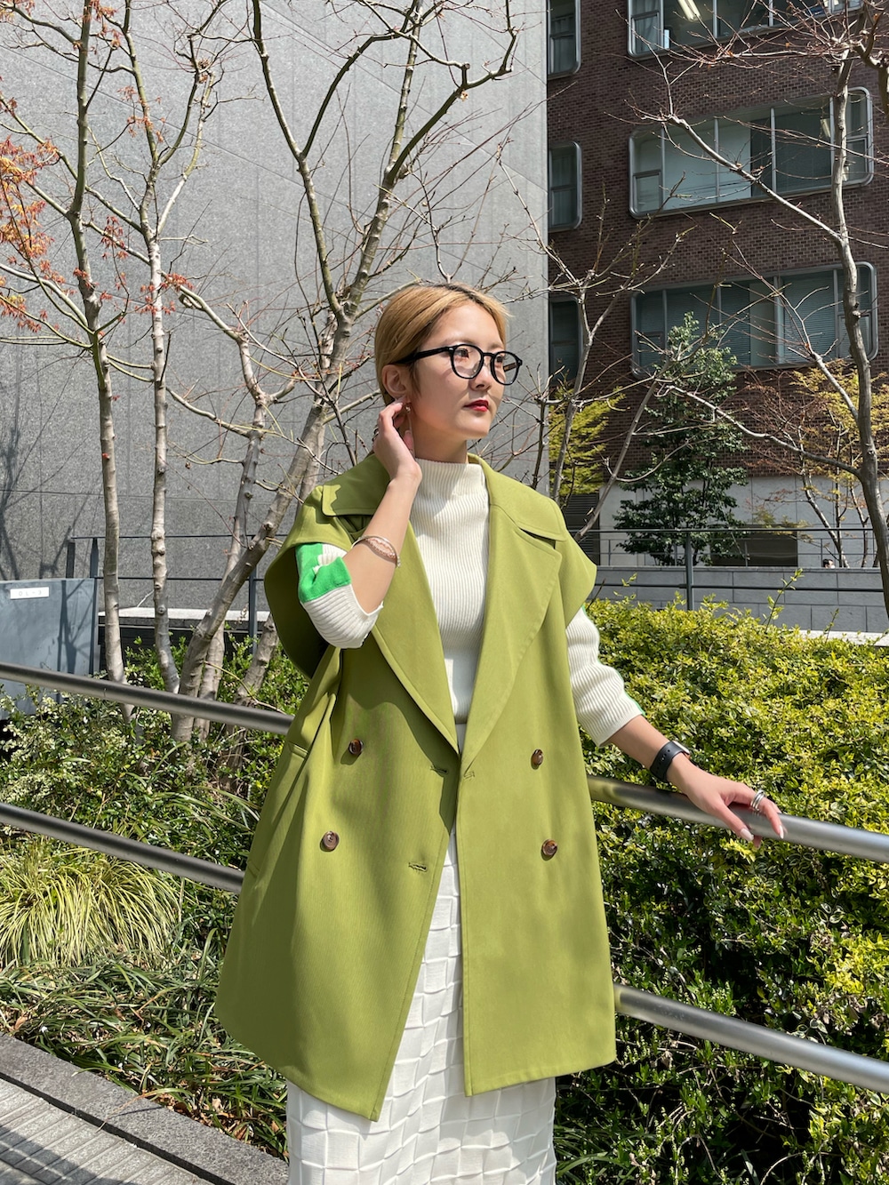 グリーン系のベスト、ホワイト系のニット/セーター、ホワイト系のスカートを着用したレディースの春コーディネートの3枚目の写真