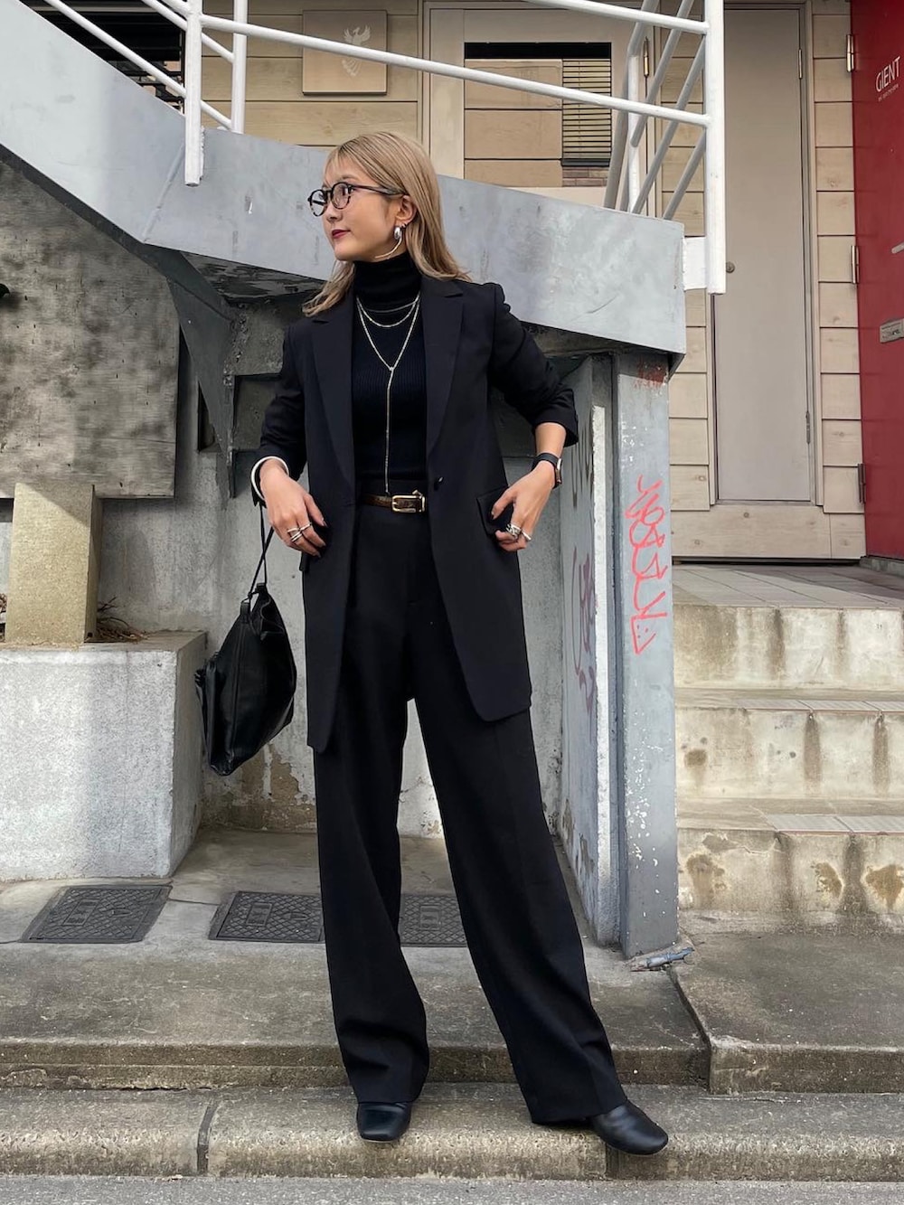 ブラック系のテーラードジャケット、ブラック系のスラックス、グリーン系のベルトを着用したレディースの冬コーディネートの2枚目の写真