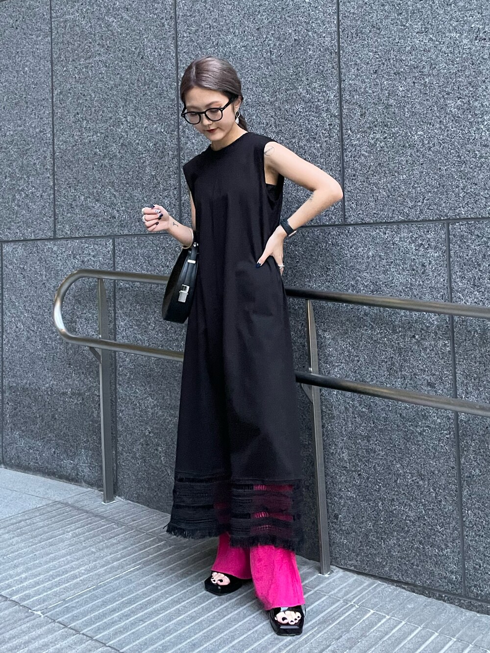 ブラック系のワンピース、ピンク系のスラックス、ブラック系のハンドバッグを着用したレディースの春コーディネートの3枚目の写真