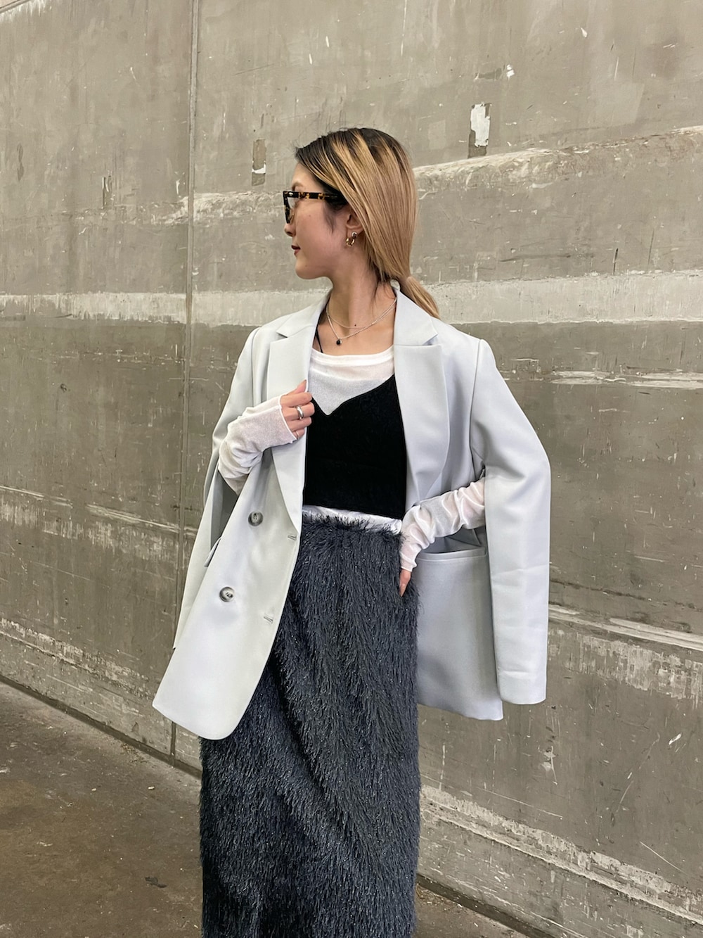 シルバー系のテーラードジャケット、グレー系のスカート、ブラック系のベストを着用したレディースの春コーディネートの2枚目の写真