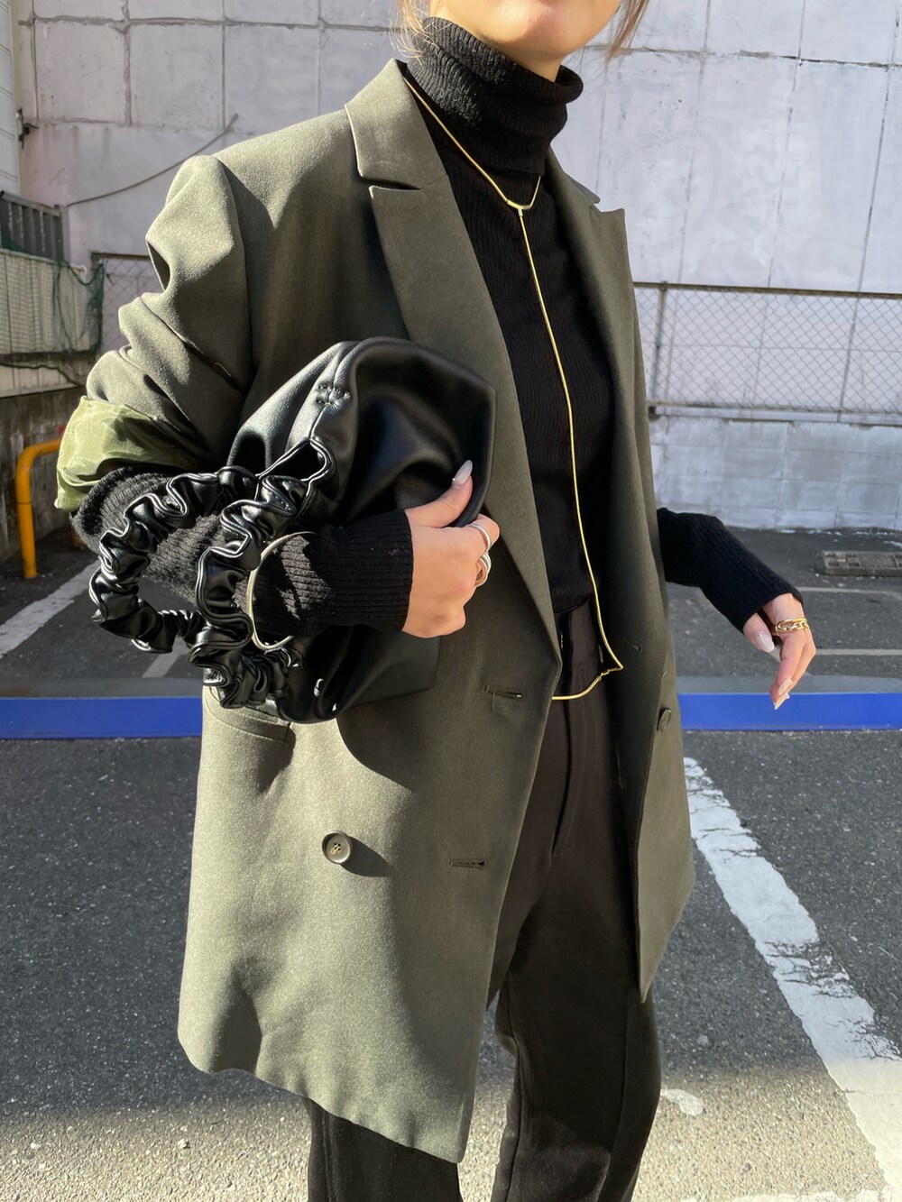 グリーン系のテーラードジャケット、ブラック系のスラックスを着用したレディースの冬コーディネートの2枚目の写真