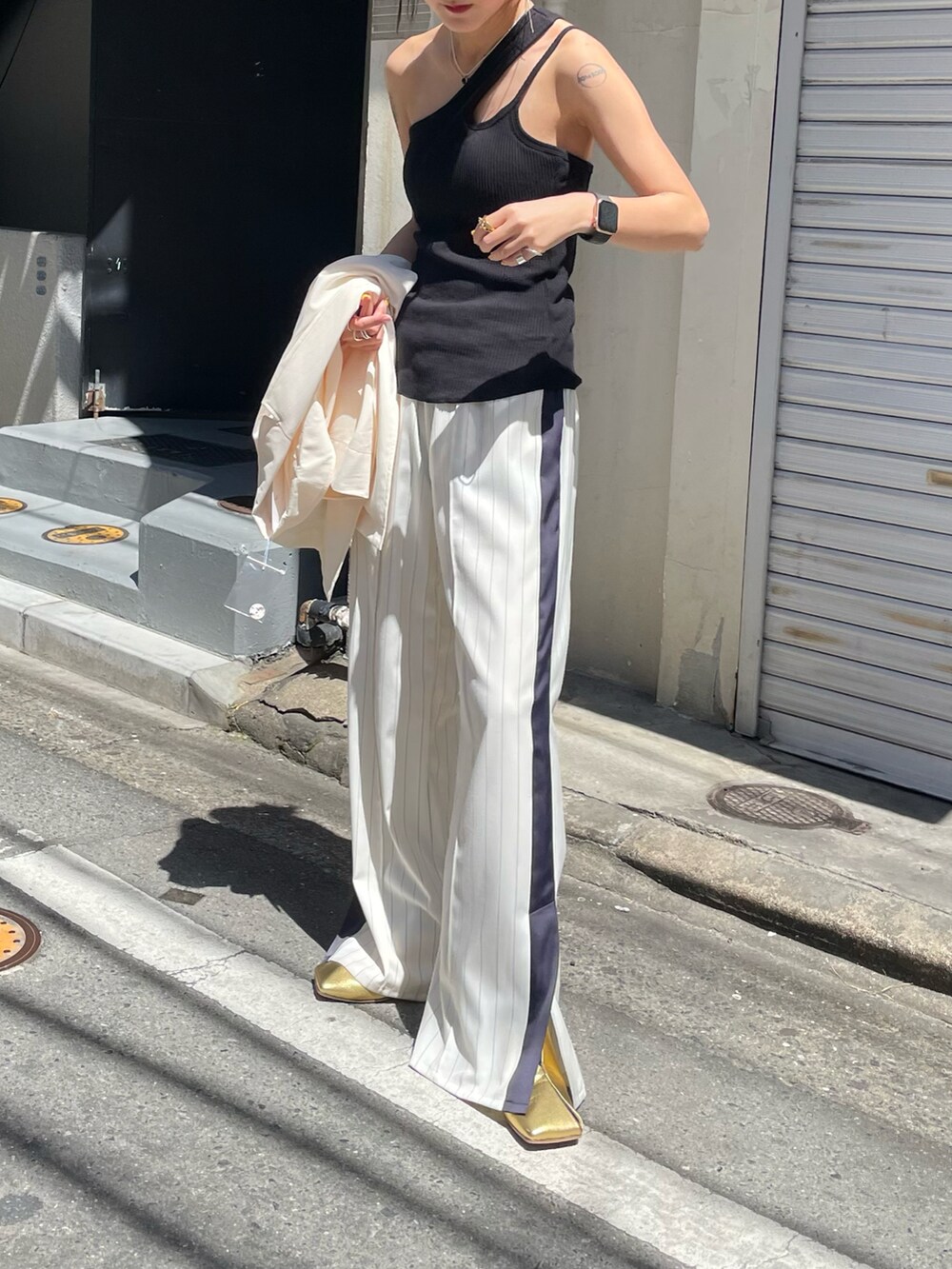 ホワイト系のスラックス、ブラック系のタンクトップを着用したレディースの春コーディネートの2枚目の写真