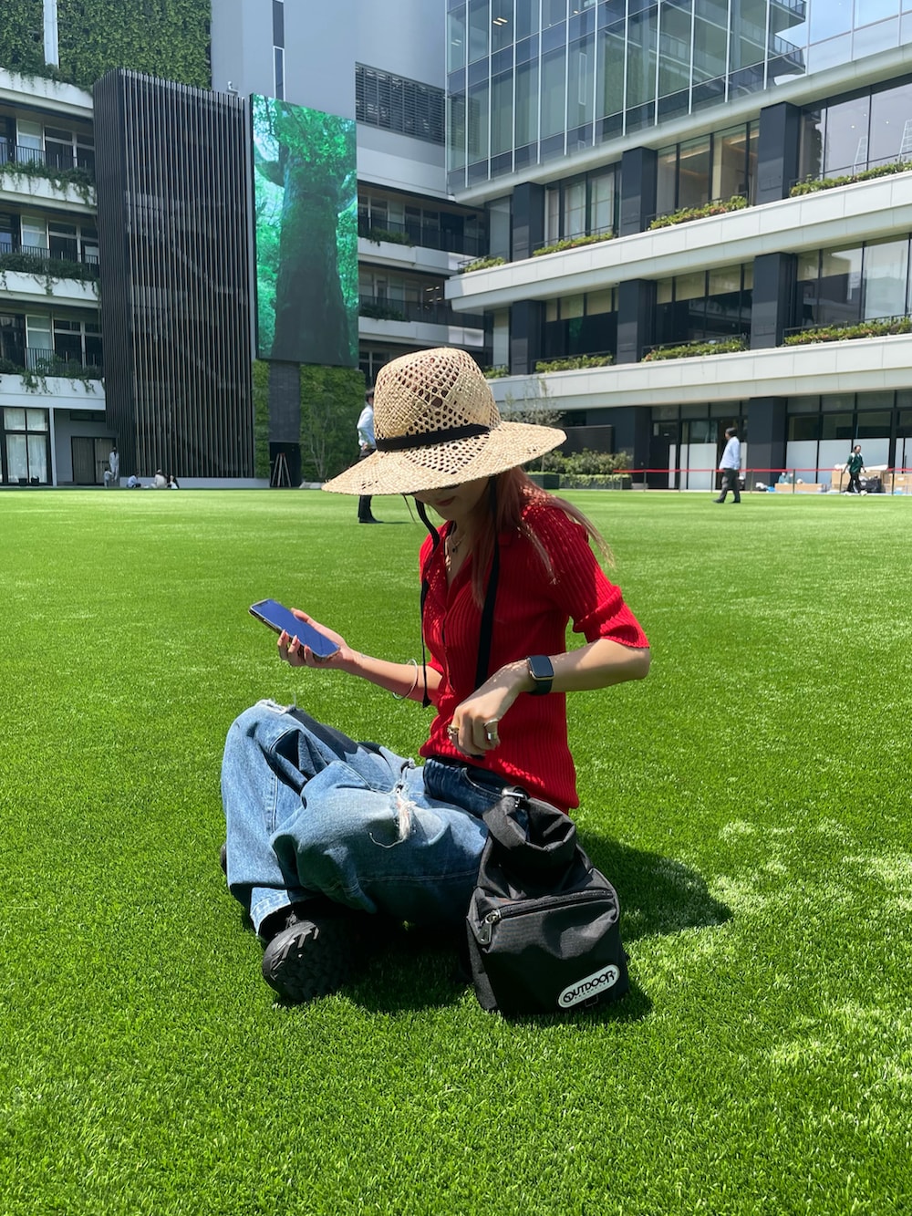 レッド系のニット/セーター、ブラック系のハンドバッグを着用したレディースの春コーディネートの2枚目の写真