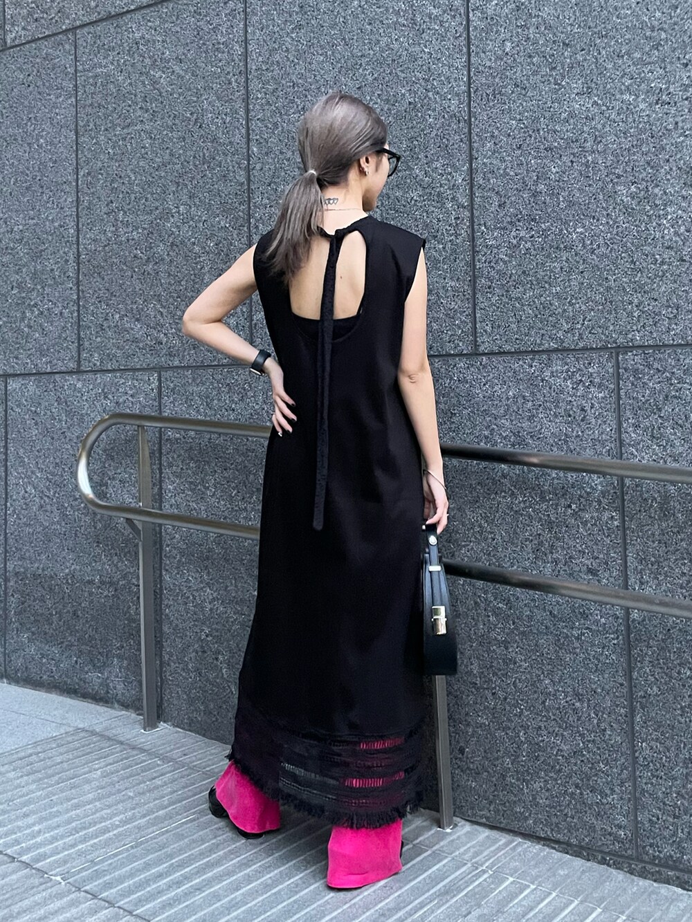 ブラック系のワンピース、ピンク系のスラックス、ブラック系のハンドバッグを着用したレディースの春コーディネートの2枚目の写真