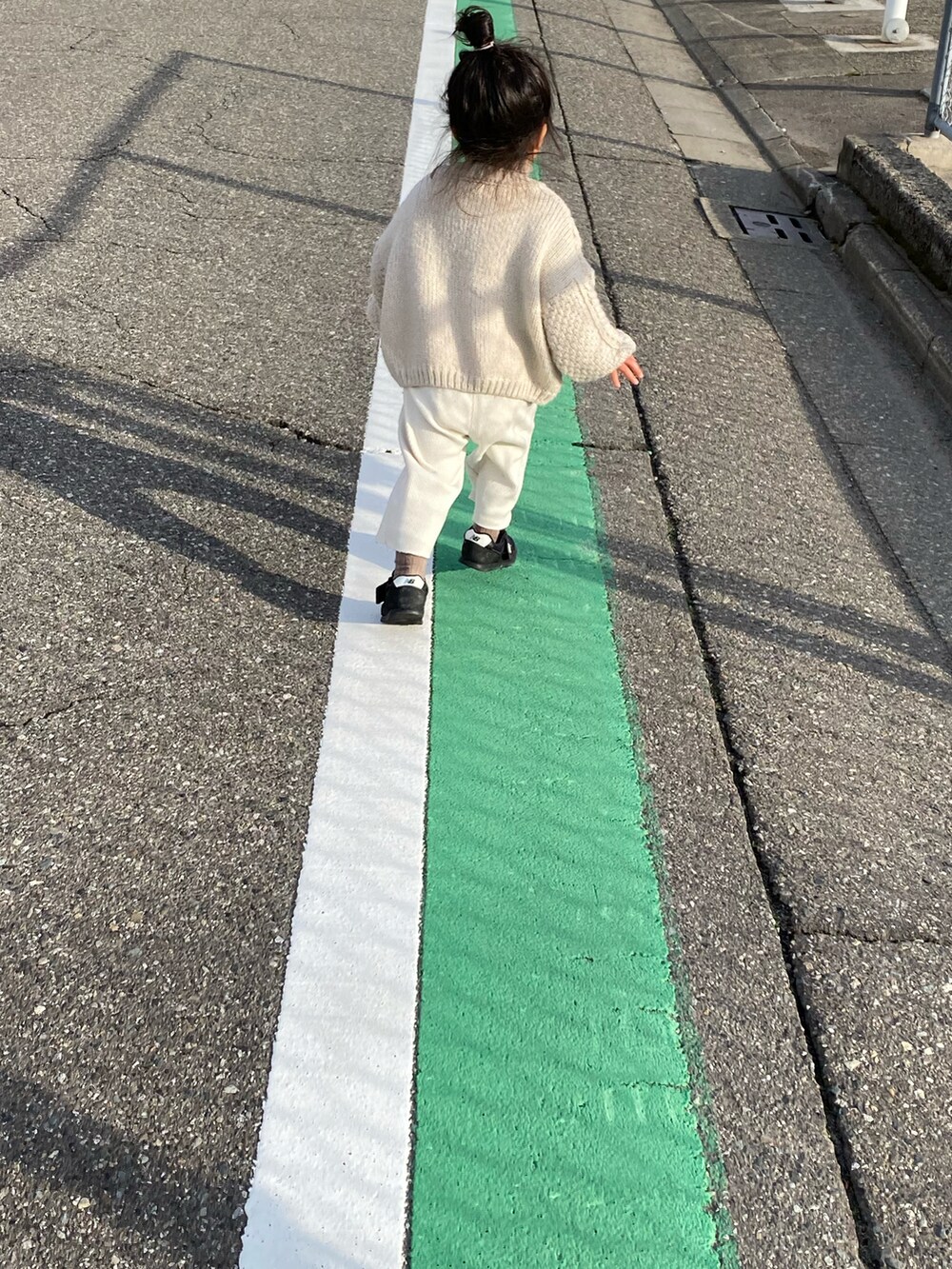 ベージュ系のカーディガン/ボレロ、ホワイト系のパンツ、ブラック系のスニーカーを着用したキッズの冬コーディネートの2枚目の写真