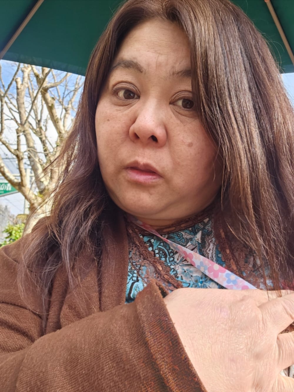 グリーン系のトップス、ブラウン系のパンツ、ブラック系のスニーカーを着用したレディースの春コーディネートの4枚目の写真