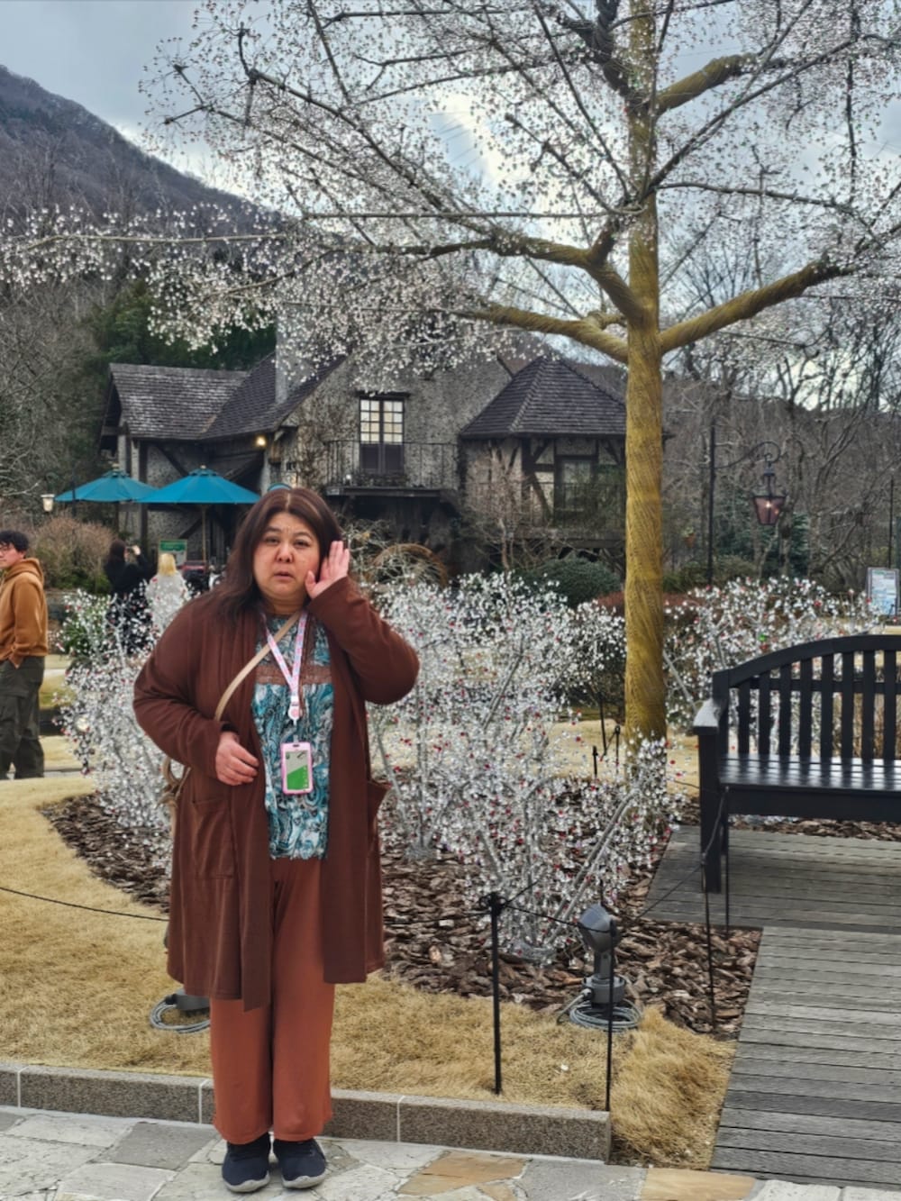 グリーン系のトップス、ブラウン系のパンツ、ブラック系のスニーカーを着用したレディースの春コーディネートの2枚目の写真