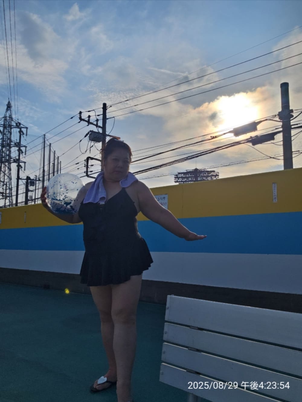 ブラック系のビーチサンダル、ブラック系の水着、パープル系のフェイスタオルを着用したレディースの夏コーディネートの3枚目の写真