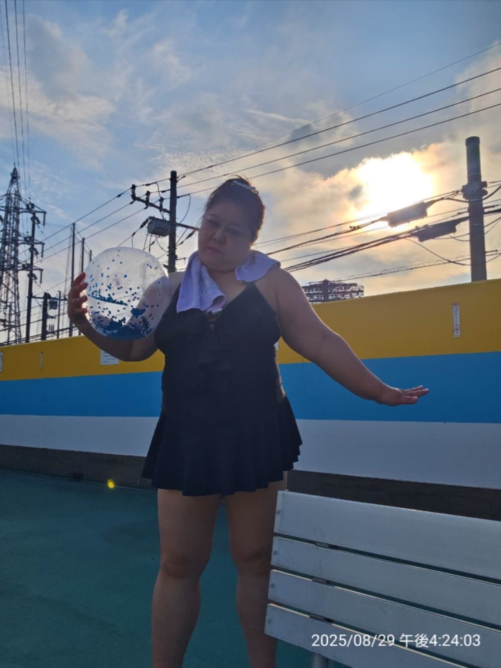 ブラック系のビーチサンダル、ブラック系の水着、パープル系のフェイスタオルを着用したレディースの夏コーディネートの4枚目の写真