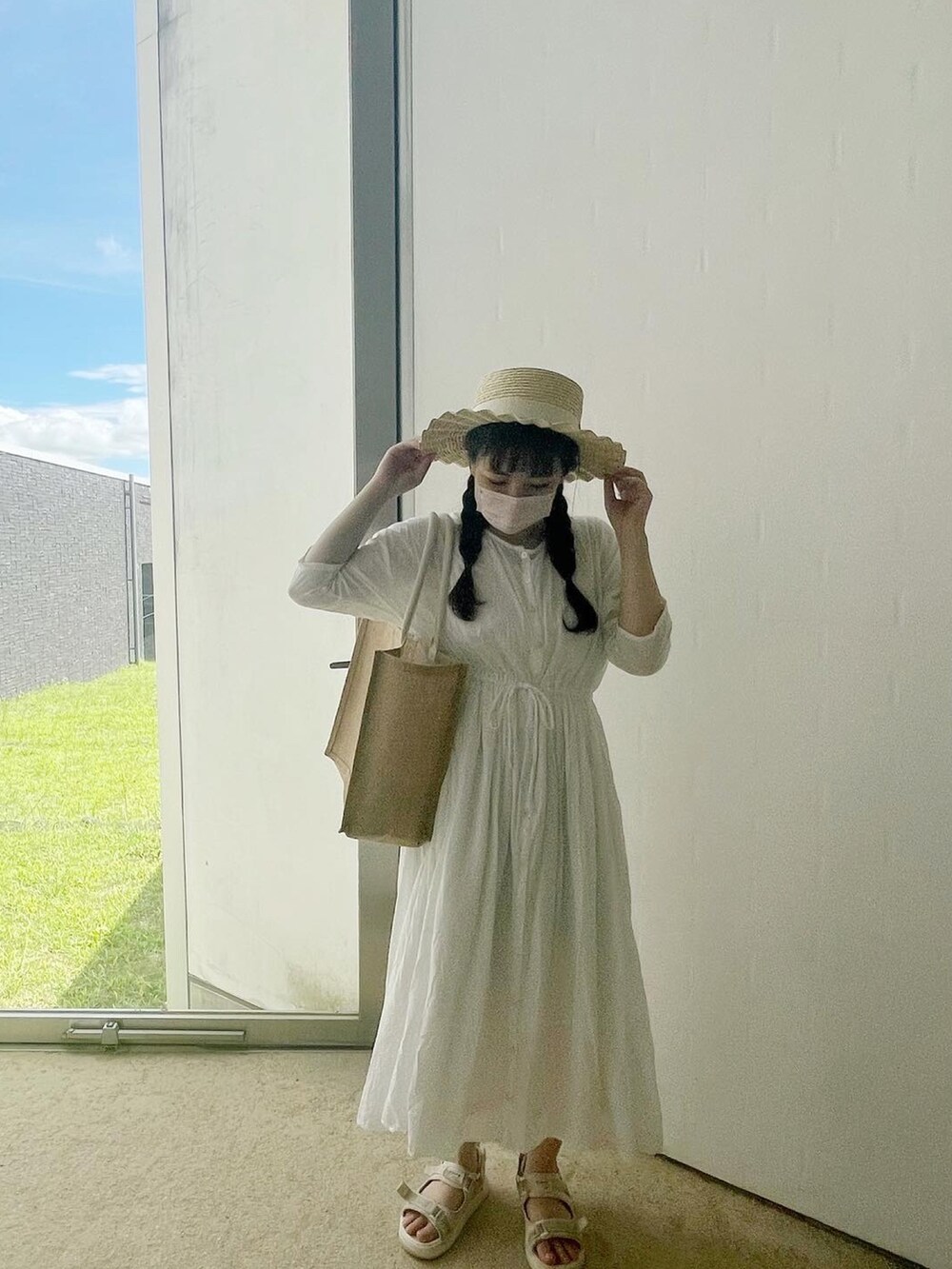 ホワイト系のワンピース、ベージュ系のバッグ、ホワイト系のハットを着用したレディースの秋コーディネートの2枚目の写真