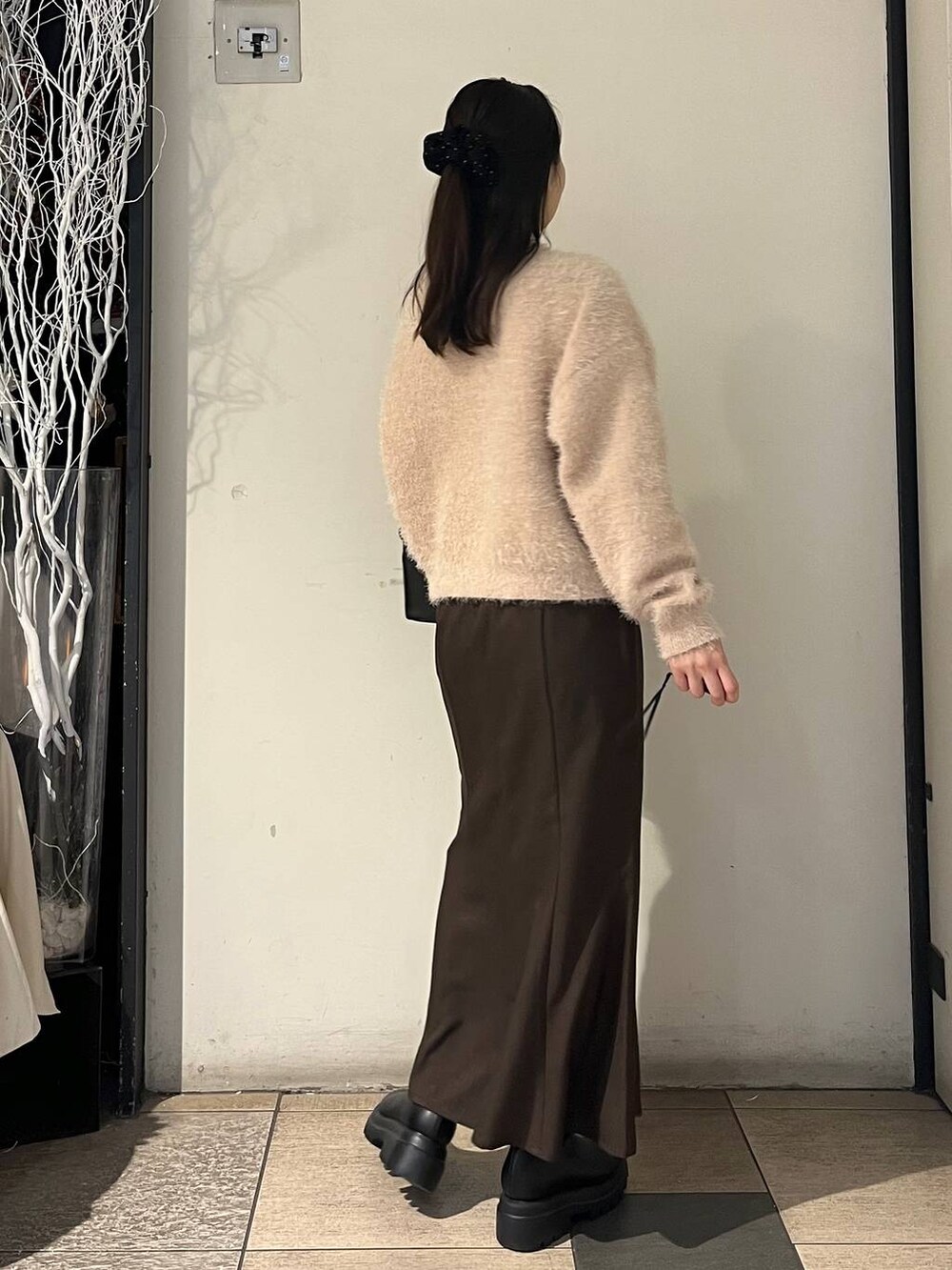 ブラック系のボストンバッグ、ブラウン系のスカート、ブラック系のブーツを着用したレディースの冬コーディネートの4枚目の写真